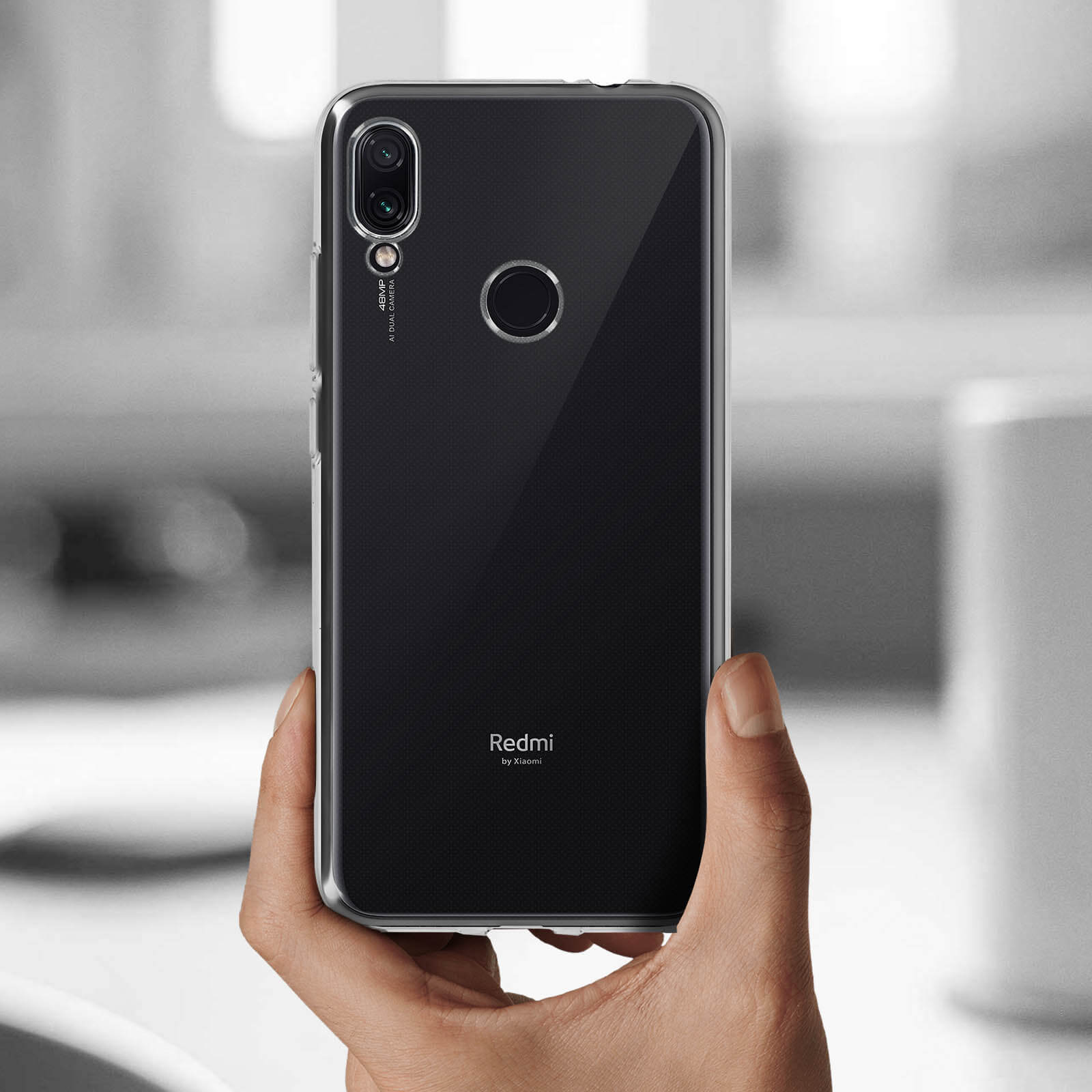 Mano che tiene un telefono con custodia trasparente. Telefono con custodia e tripla fotocamera.