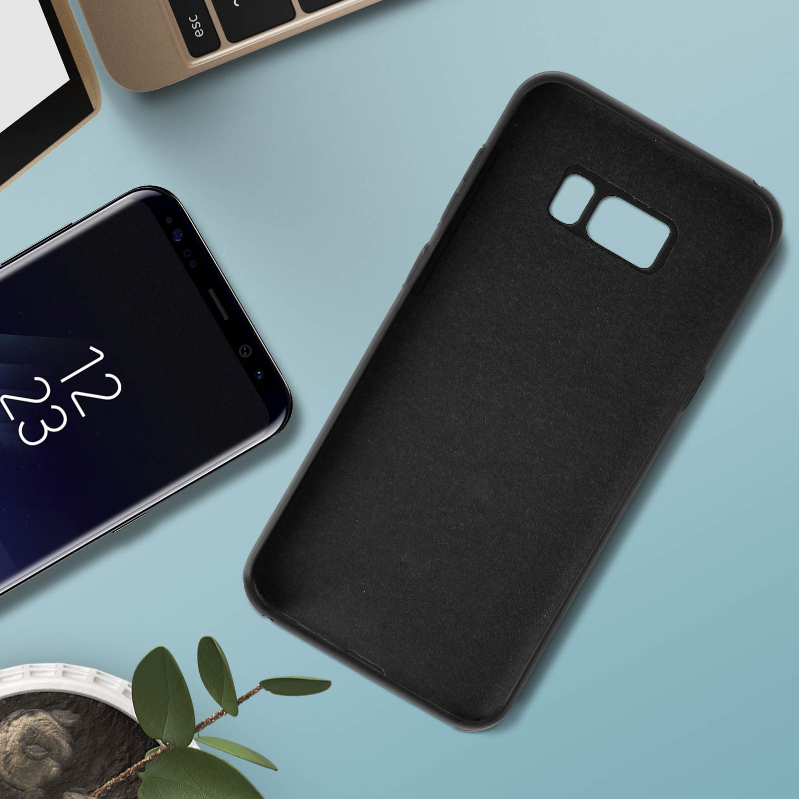 Funda y teléfono negros sobre superficie azul. Un portátil en el fondo.