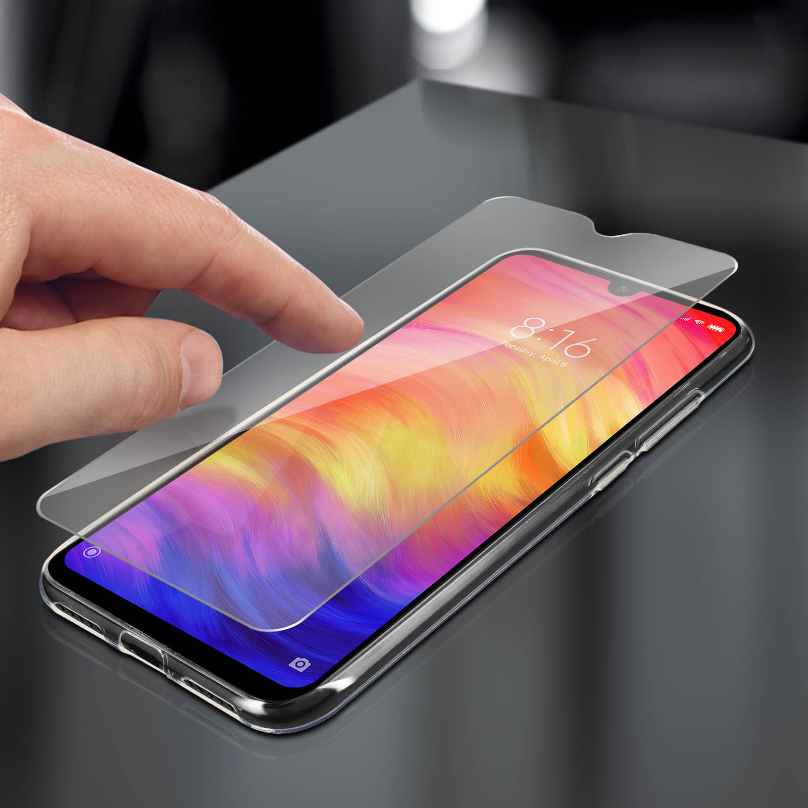 Mano che applica una protezione per lo schermo su un telefono. Il telefono ha uno sfondo colorato.