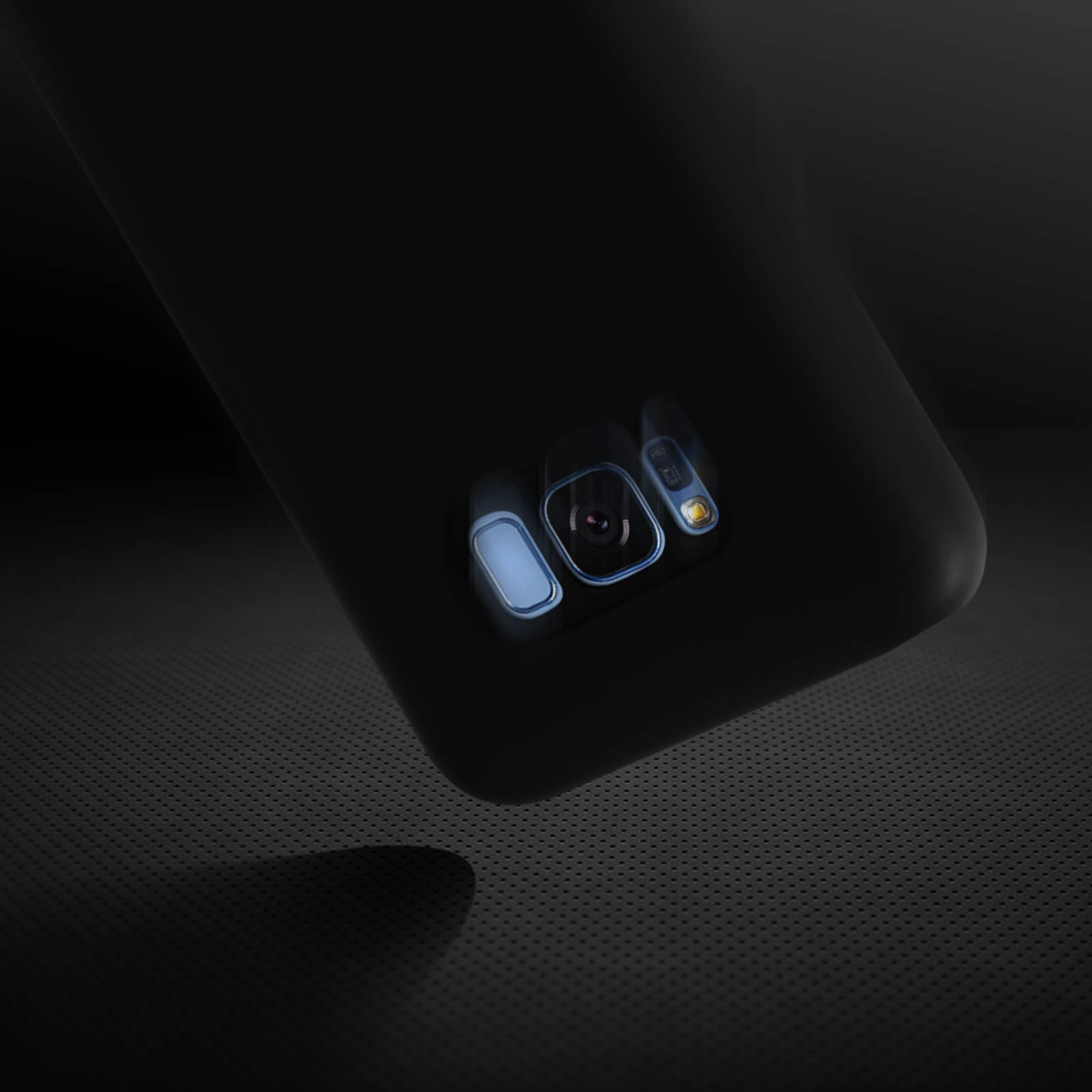 Parte trasera de teléfono negro con lentes de cámara. Sombra en superficie punteada.