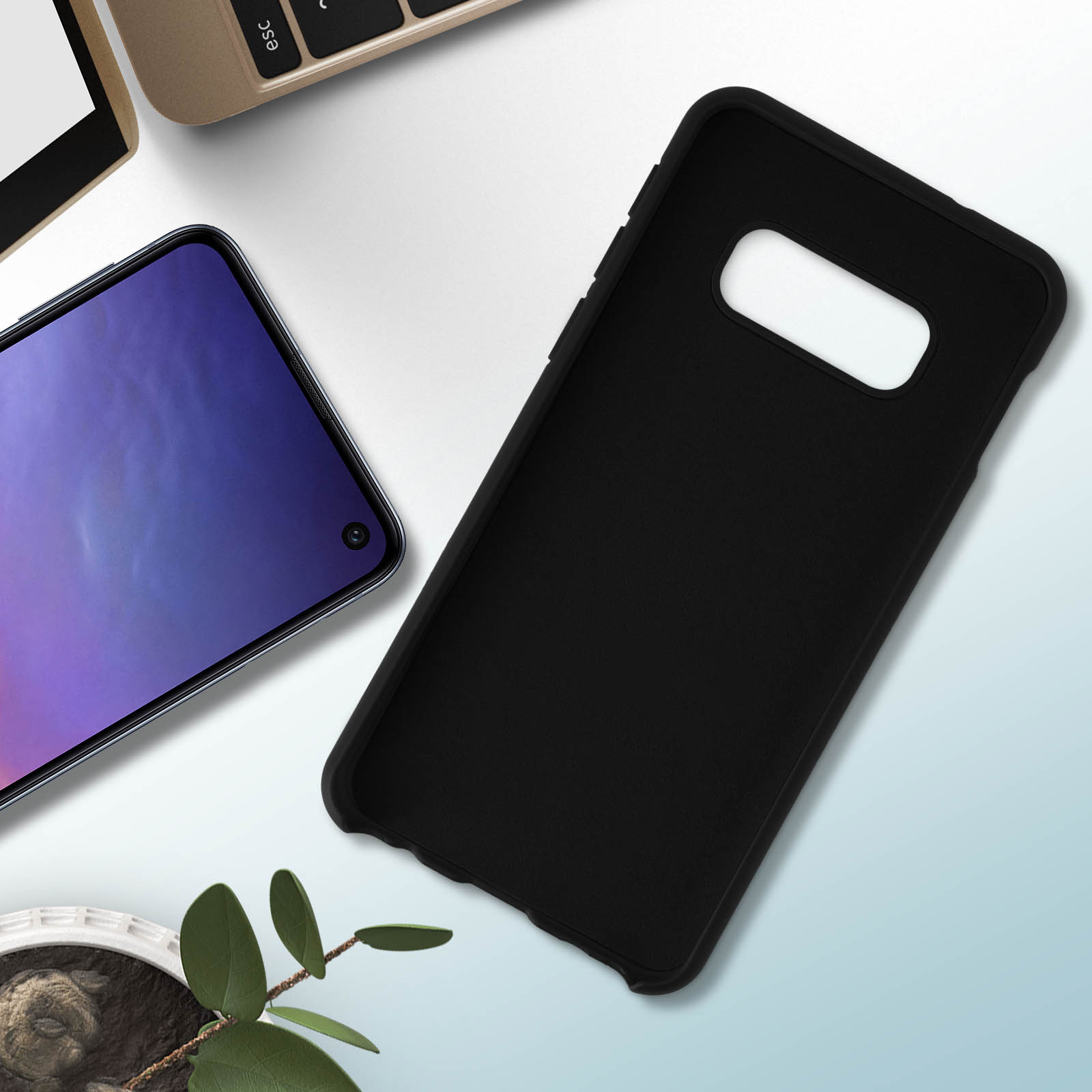 Coque de téléphone noire avec un téléphone. Clavier et plante visibles. Arrière-plan flou.