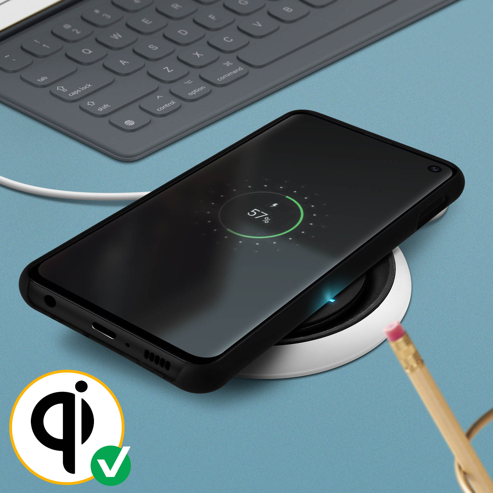 Téléphone noir se chargeant sans fil. Écran affiche 57%. Chargeur sans fil, crayon et clavier visibles.