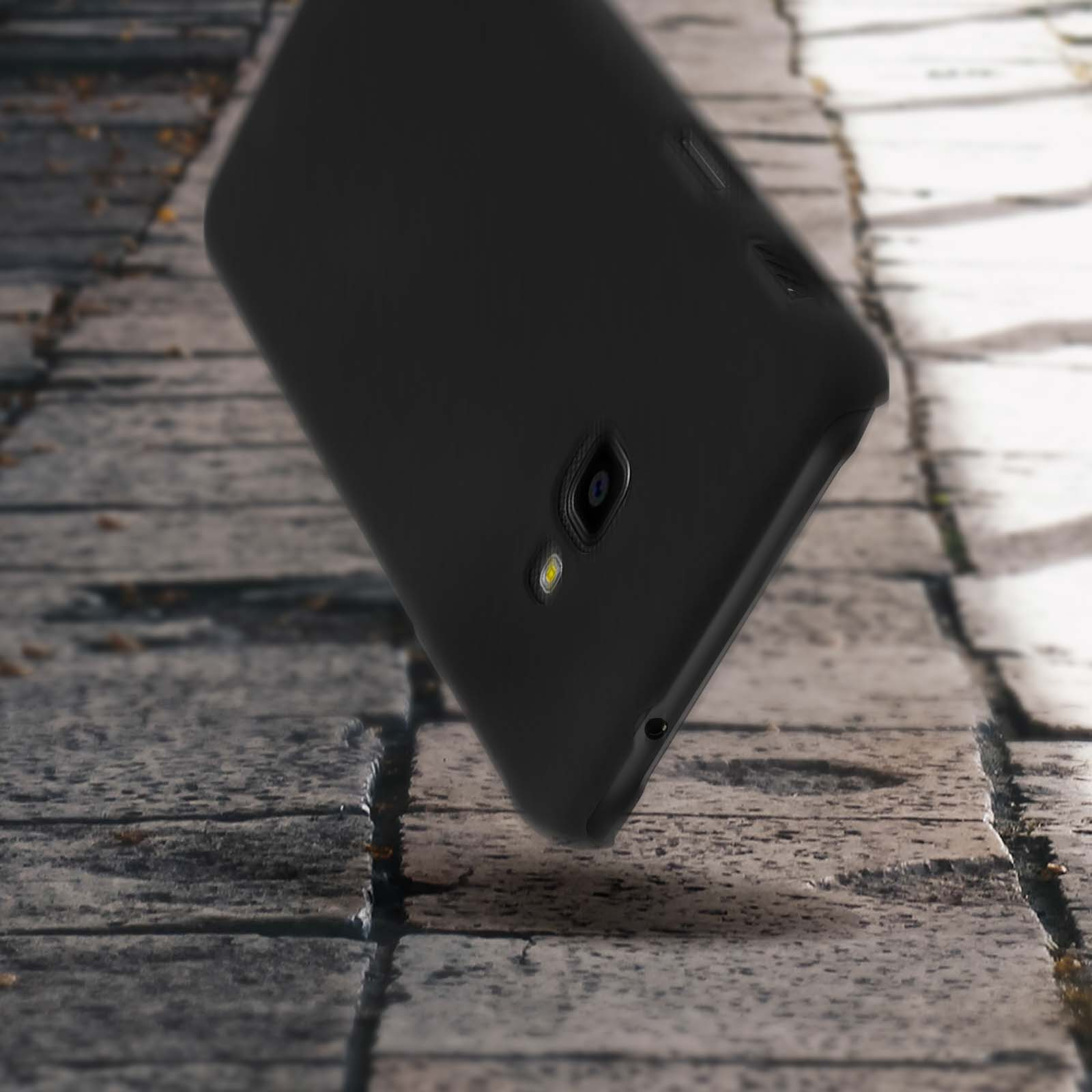 Un telefono nero su una superficie di mattoni, con sfondo sfocato.