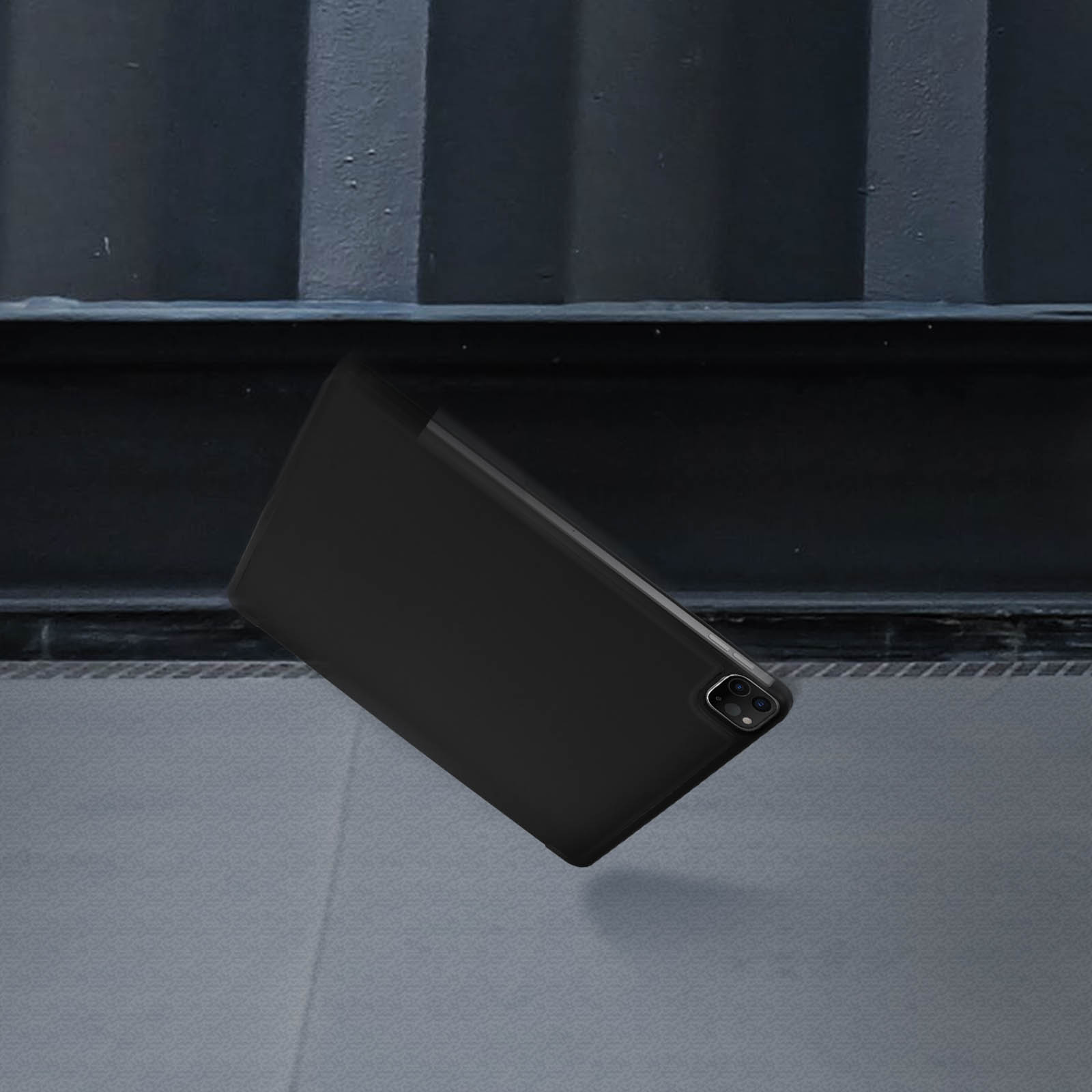 Custodia nera per tablet in aria davanti a uno sfondo scuro.