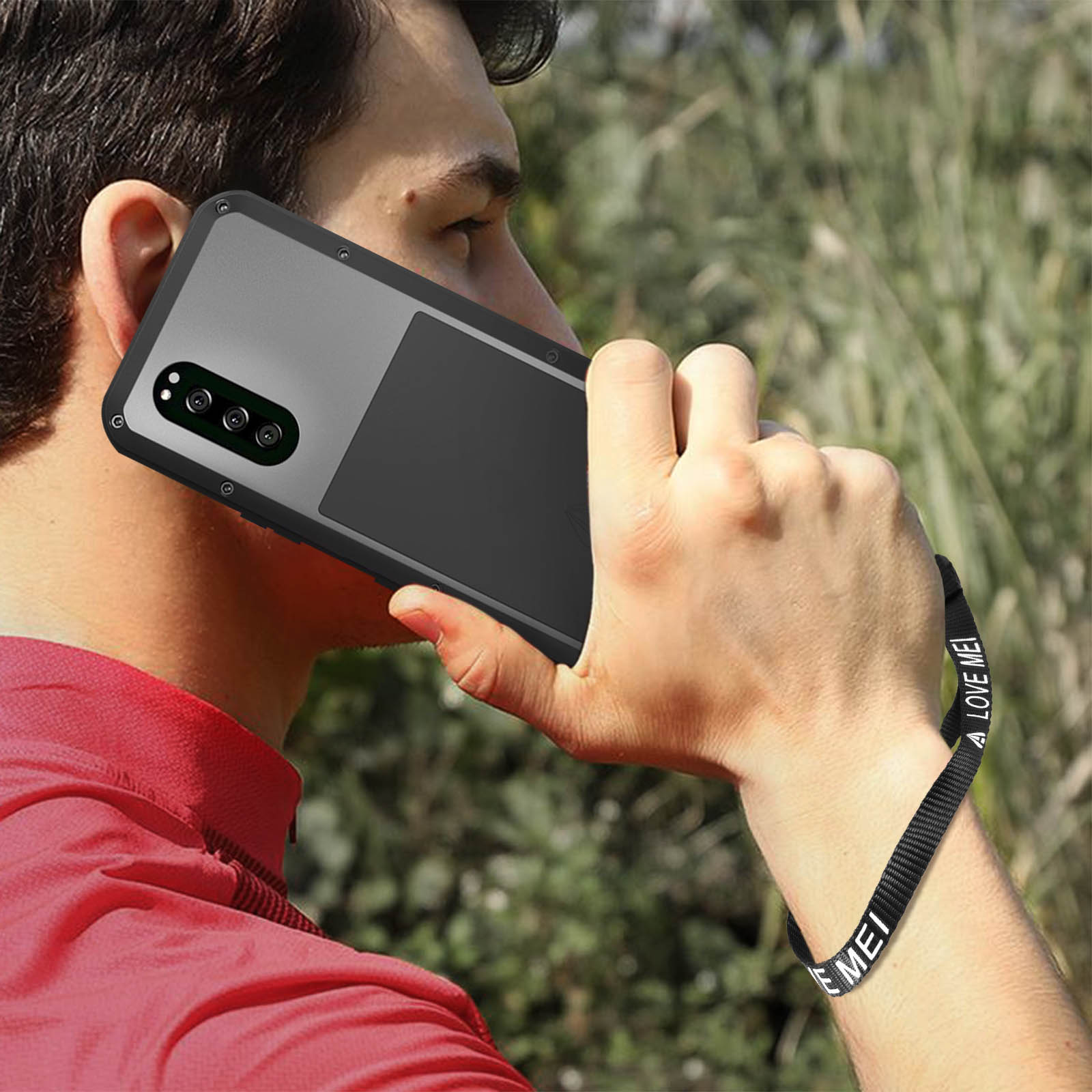 Une personne tenant un téléphone avec une sangle, parlant dans le téléphone.