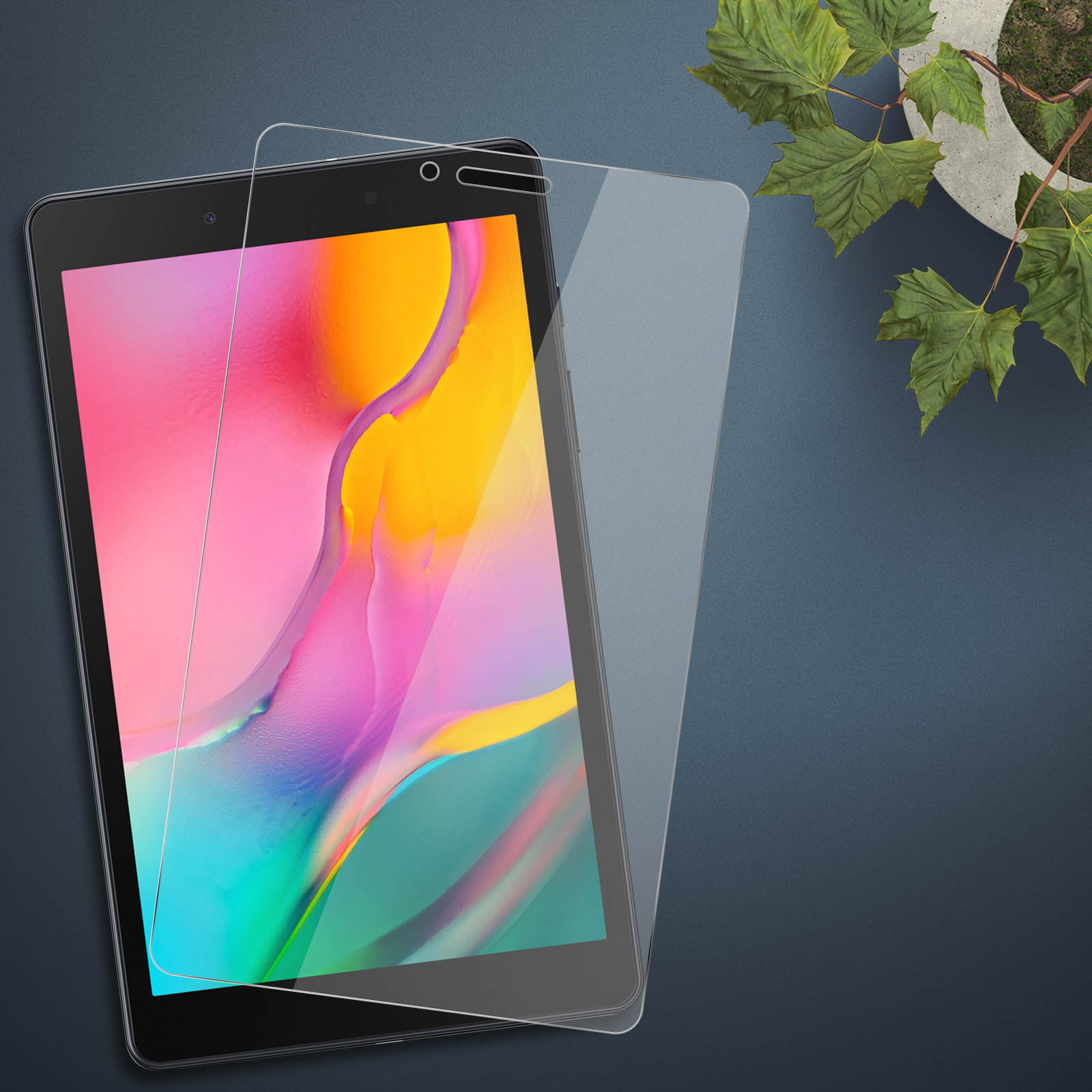 Un tablet ha un proteggi schermo applicato. Una piccola pianta in vaso è sullo sfondo.