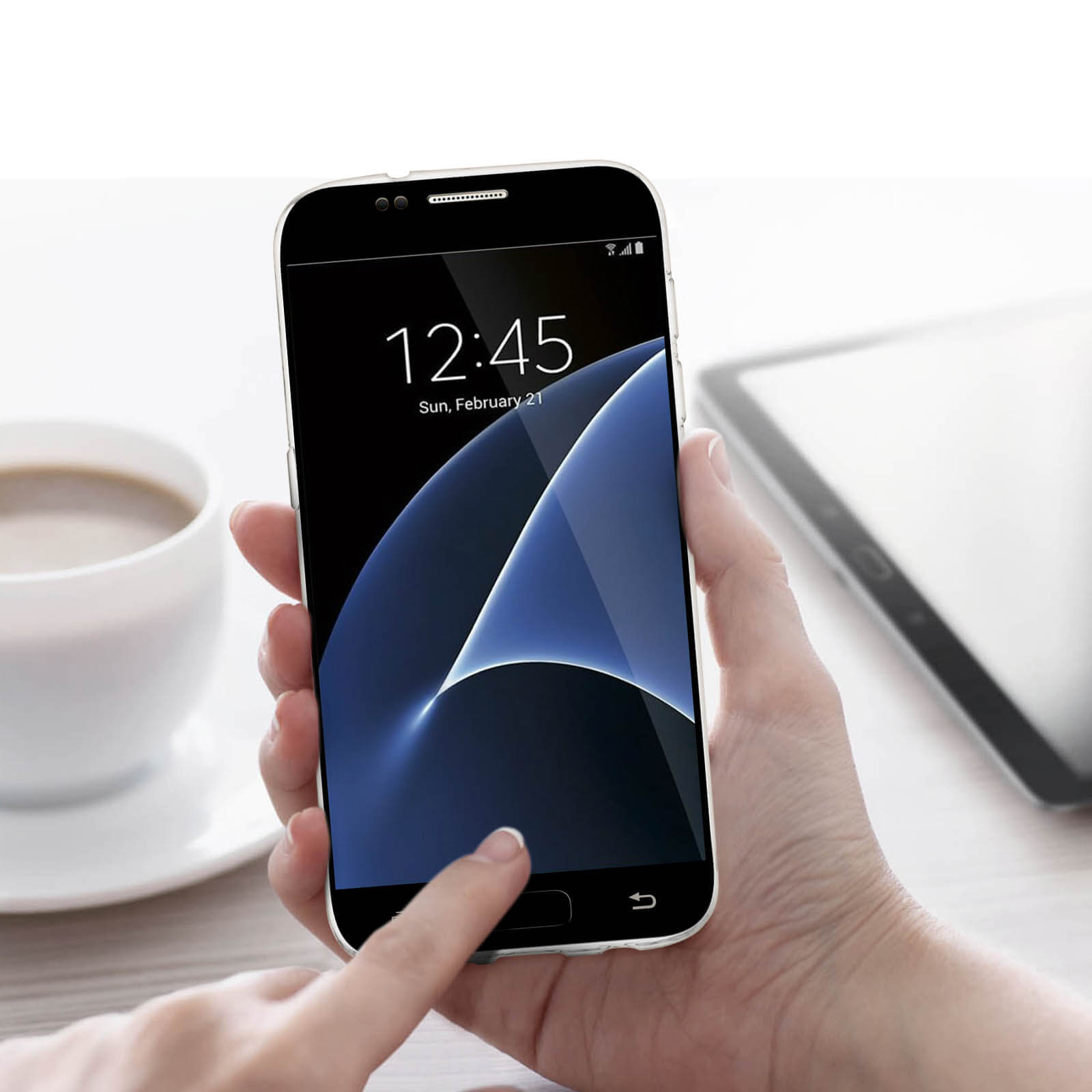 Una mano che tiene uno smartphone che mostra l'ora 12:45. Una tazza di caffè è nelle vicinanze.