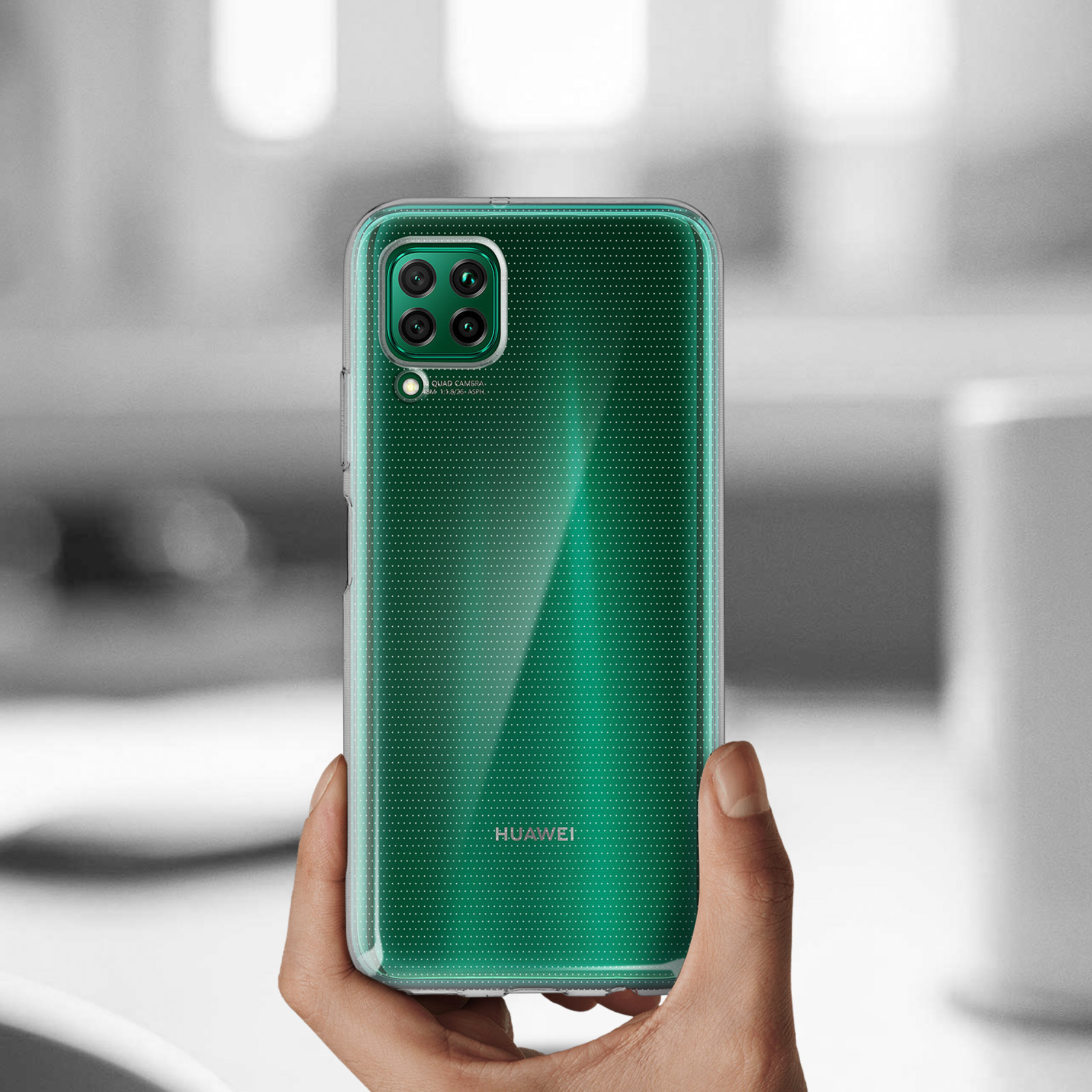 Main tenant un téléphone vert avec coque transparente. La coque est à pois, appareils photo.