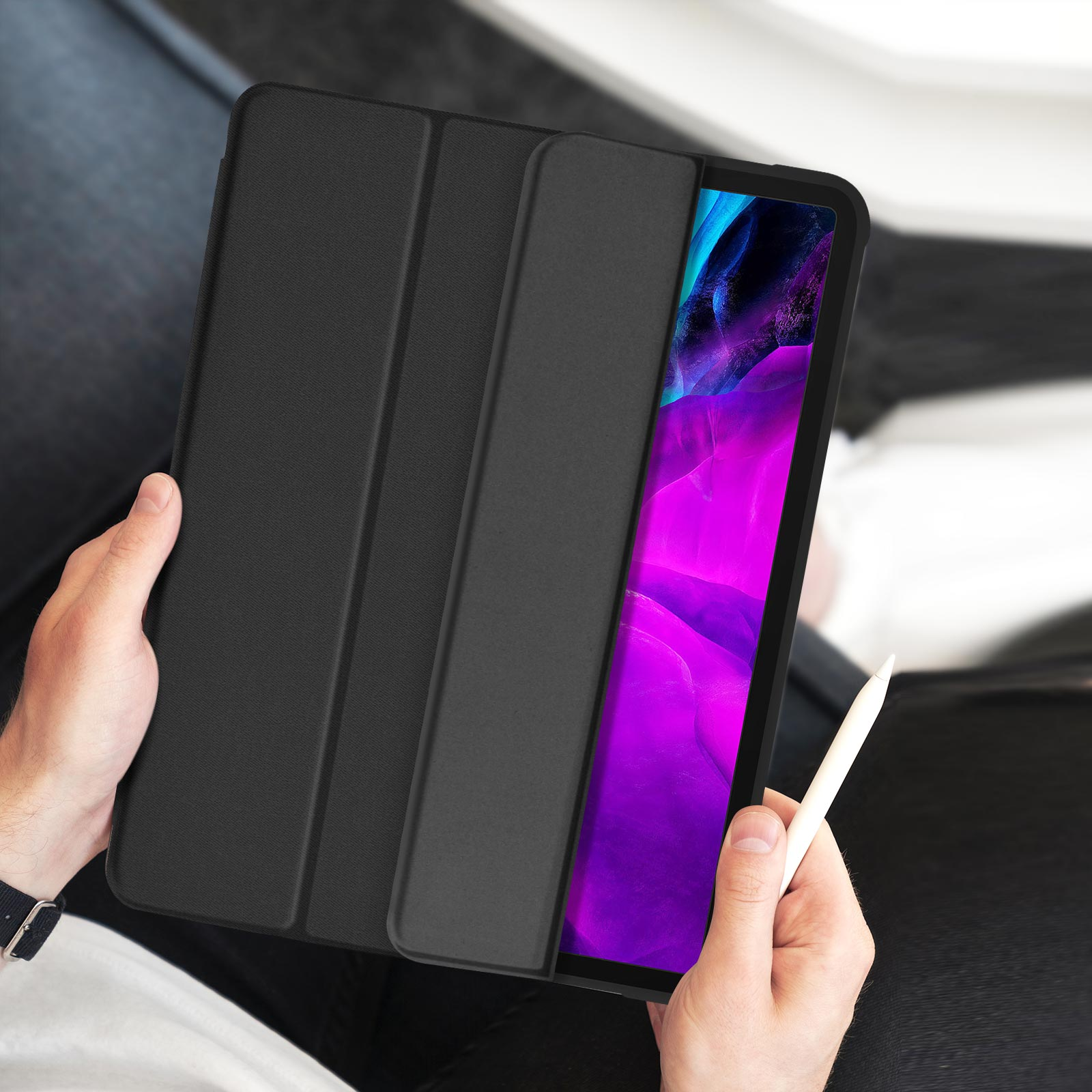 Persona che tiene una custodia nera per tablet con un tablet all'interno. Il tablet ha uno sfondo viola e bianco.
