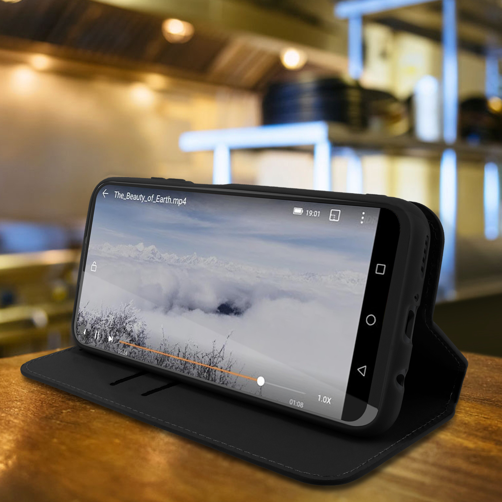 Telefono che mostra un video all'interno di una custodia nera, aperto. Sfondo tavolo di legno.