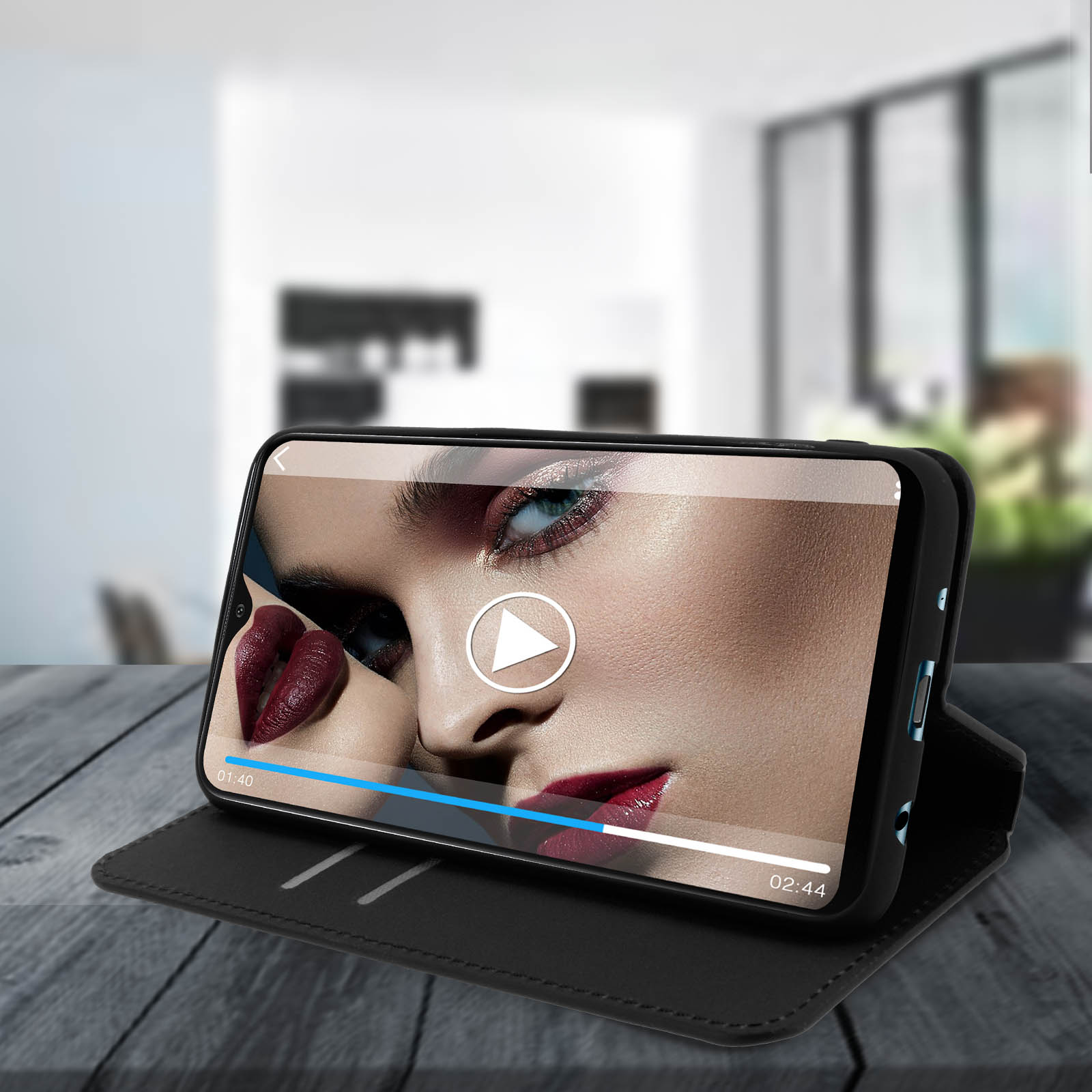 Un téléphone lisant une vidéo sur un étui noir sur une table en bois. La vidéo est celle d'une femme.
