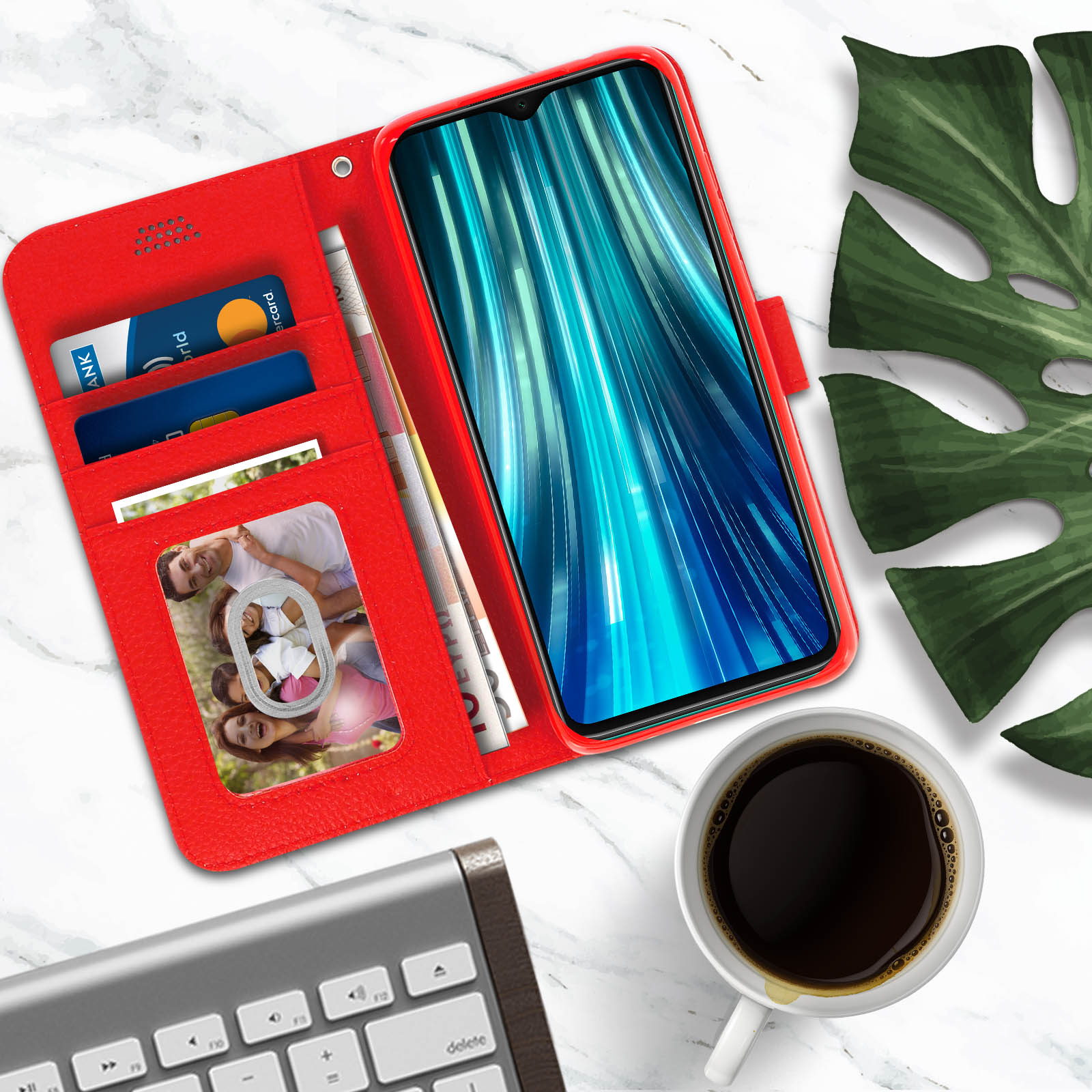 Rode telefoonhoes met een familiefoto en bankpas. Er is een kop koffie en een toetsenbord.