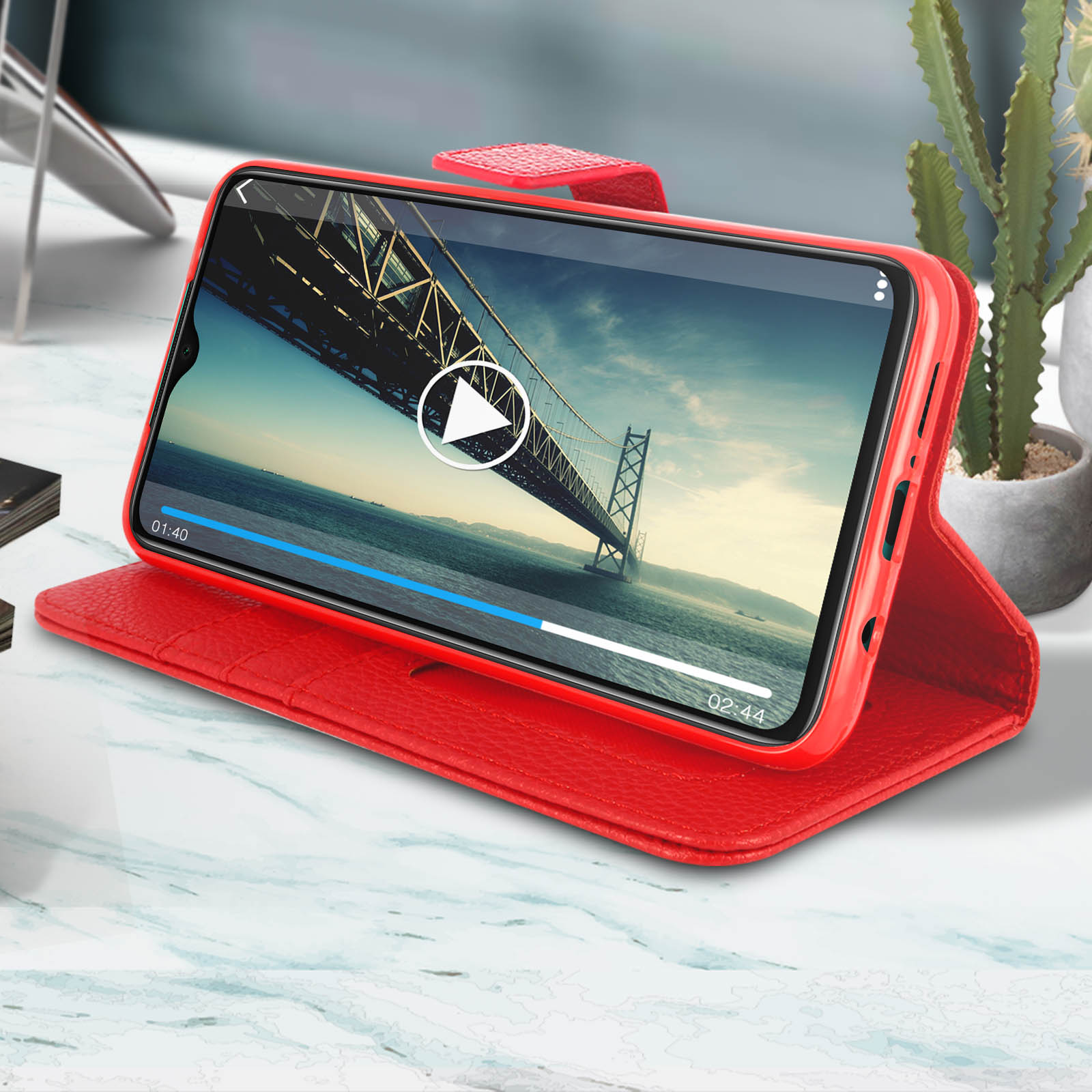 Een telefoon met een video die wordt afgespeeld in een rode telefoonhoes. De hoes ligt op een tafel.