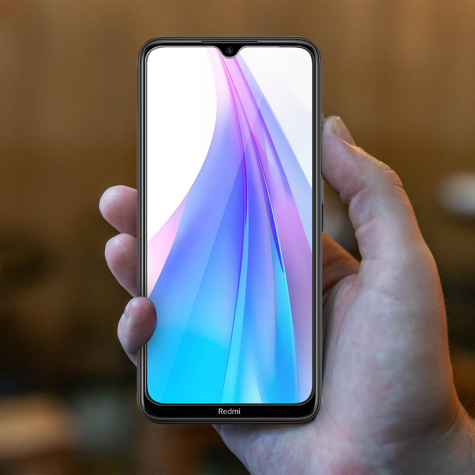 Mano che tiene un telefono con un display colorato. Il telefono mostra un logo Redmi.