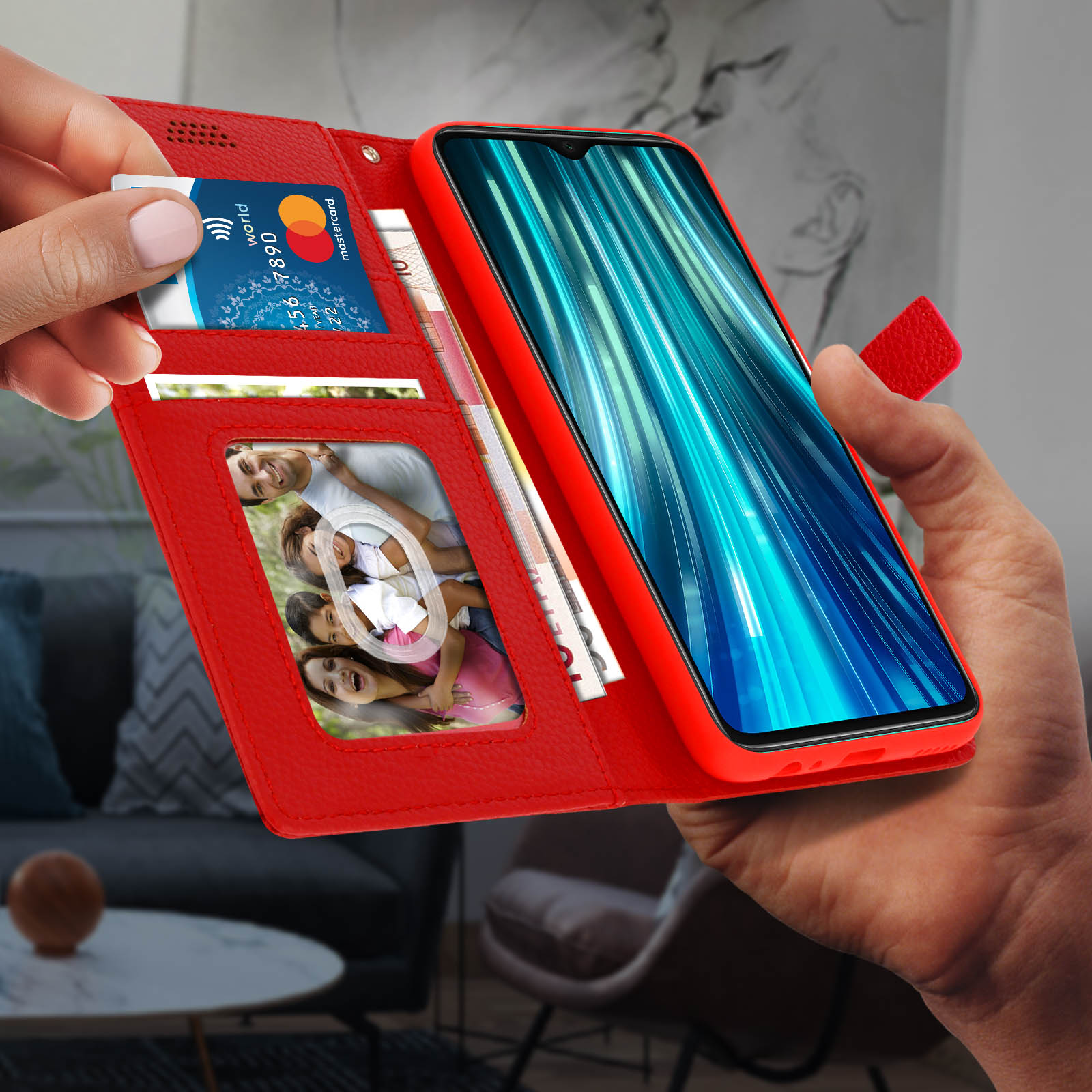 Rode telefoonhoes open, een telefoon en kaartsleuven onthullend. Bankkaarten en contant geld zichtbaar. Hand vasthoudend.