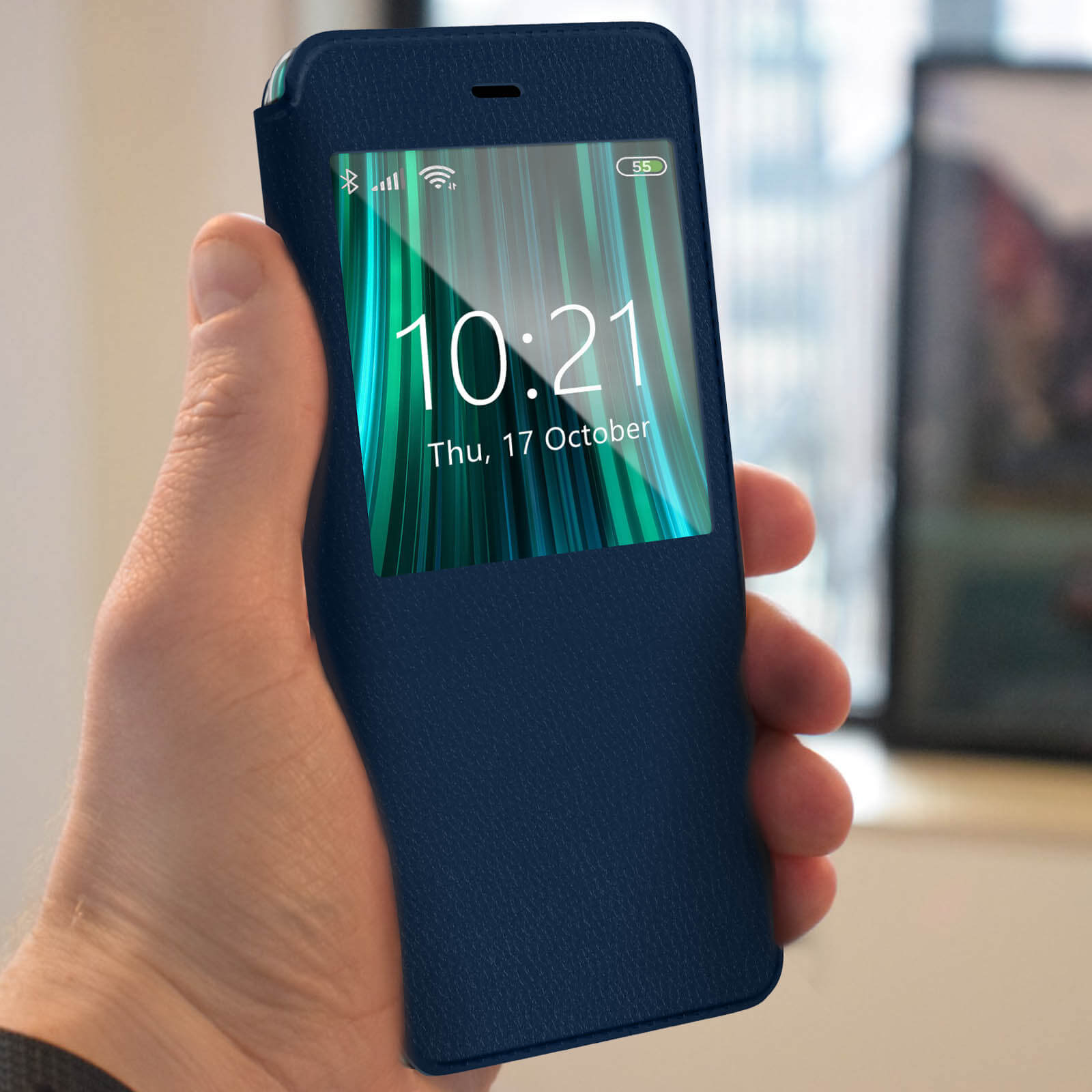Una mano tiene uno smartphone con lo schermo che mostra l'ora e le notifiche. Il telefono è in una custodia blu.