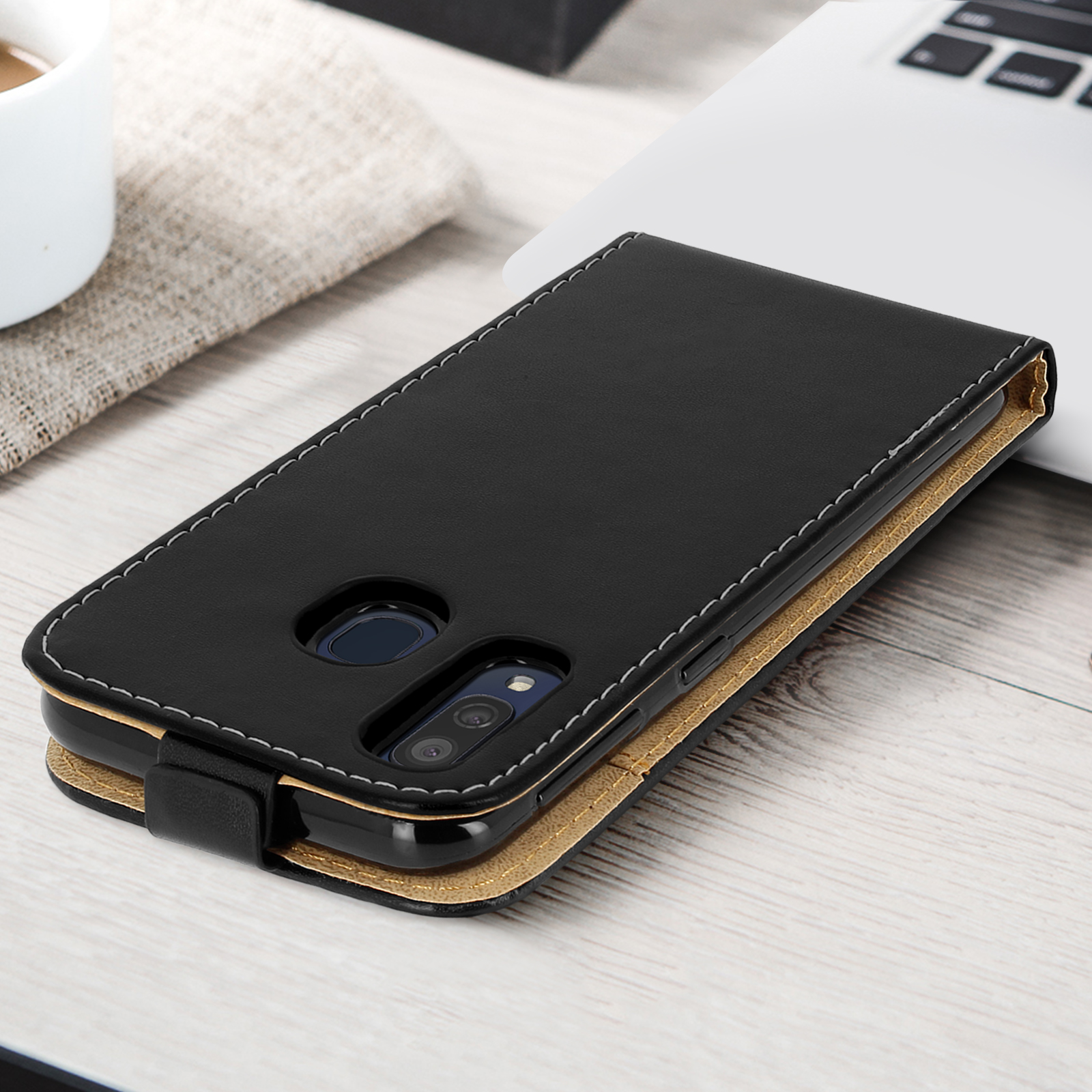 Una custodia nera in pelle, aperta, con un telefono all'interno. Cuciture bianche e oro.