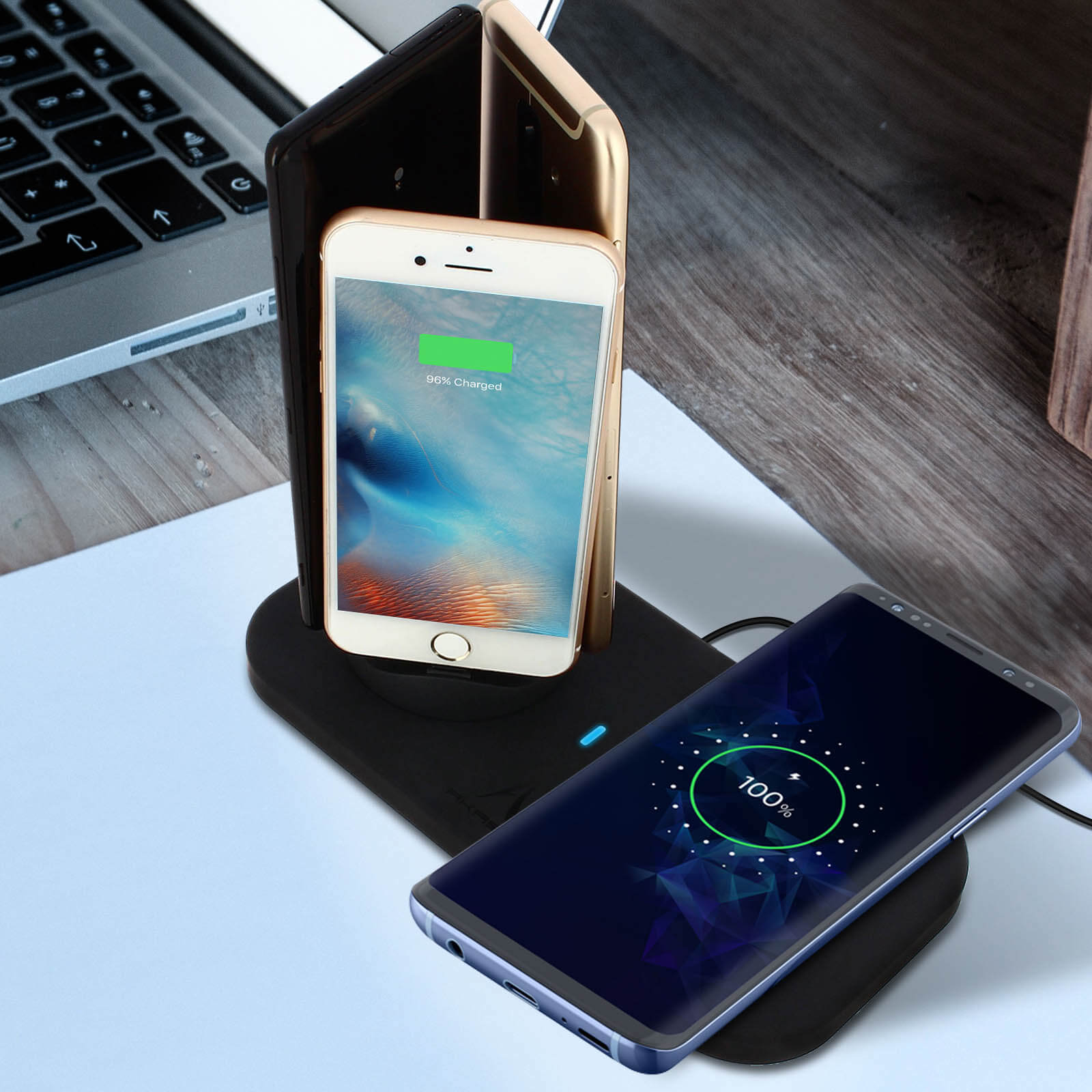 Tres teléfonos cargando en un cargador inalámbrico. Un teléfono muestra 100% cargado.