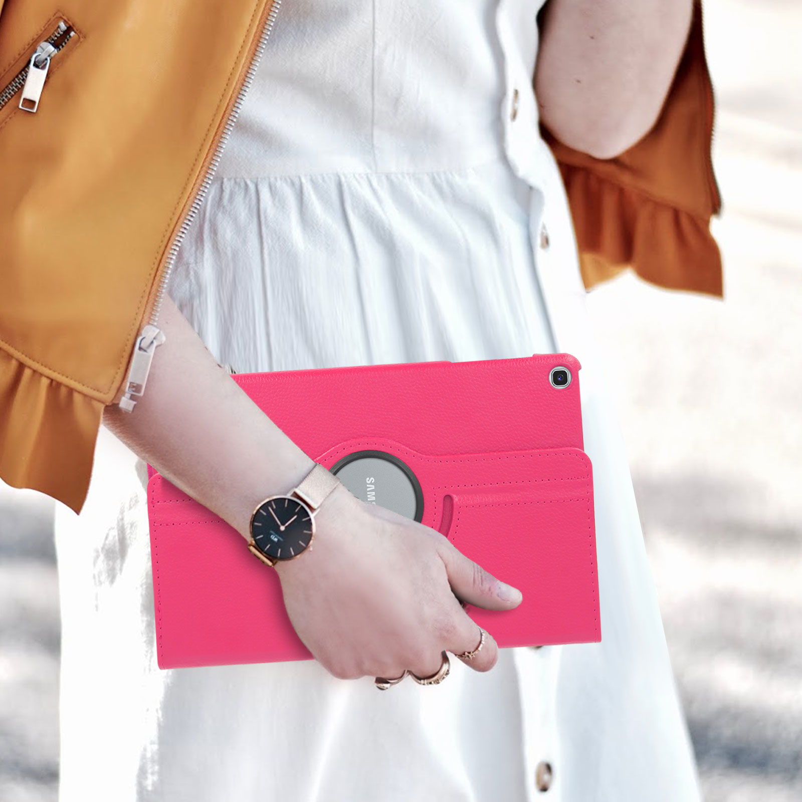 Una donna tiene una custodia per tablet rosa. Orologio e anelli sul polso e sulle dita della donna.