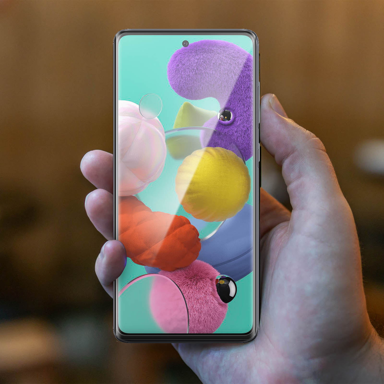 Hand die een smartphone vasthoudt. Scherm toont cartoongezichten. Vage achtergrond. De hand is scherp.