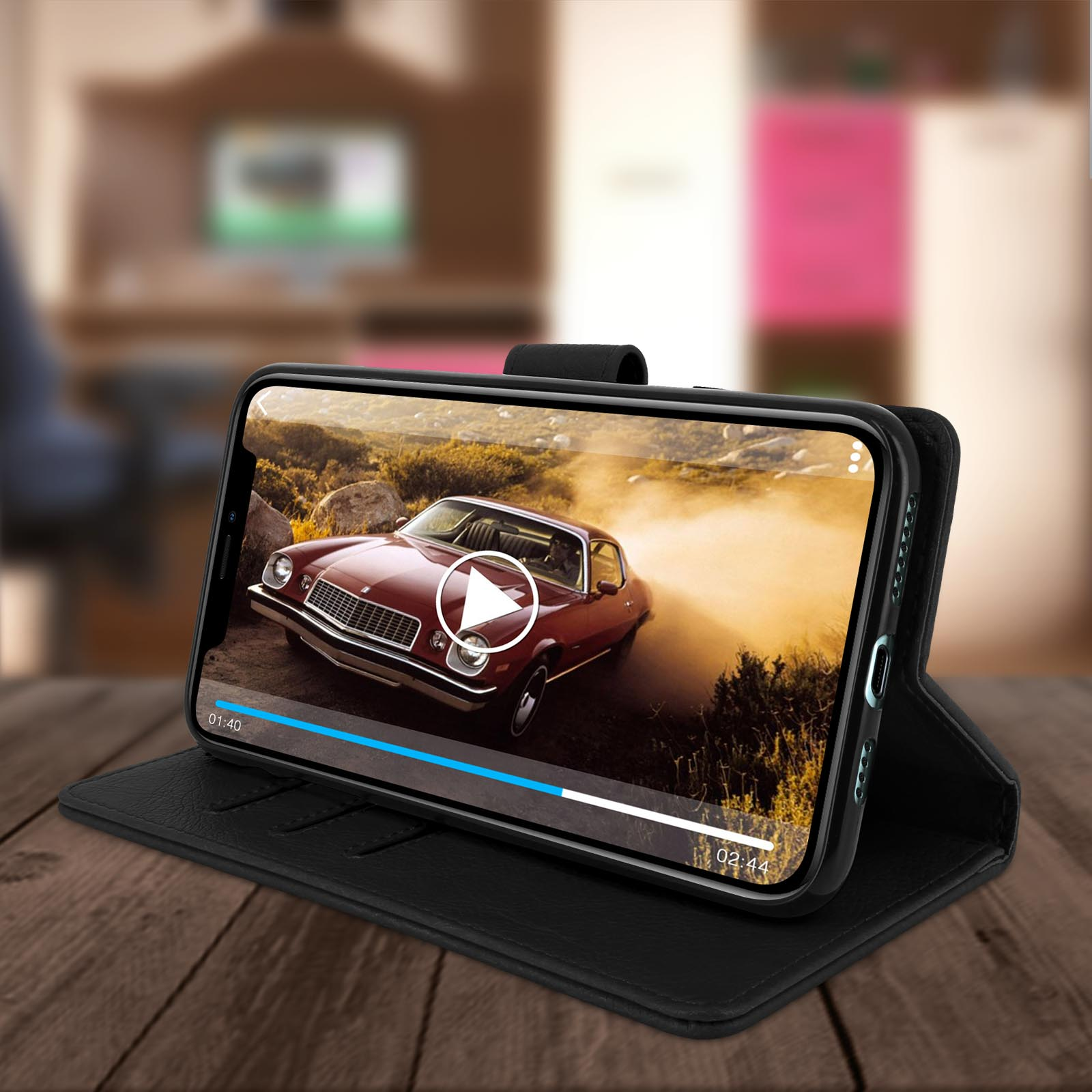 Téléphone dans un étui noir, lisant une vidéo de voiture, sur une table en bois.