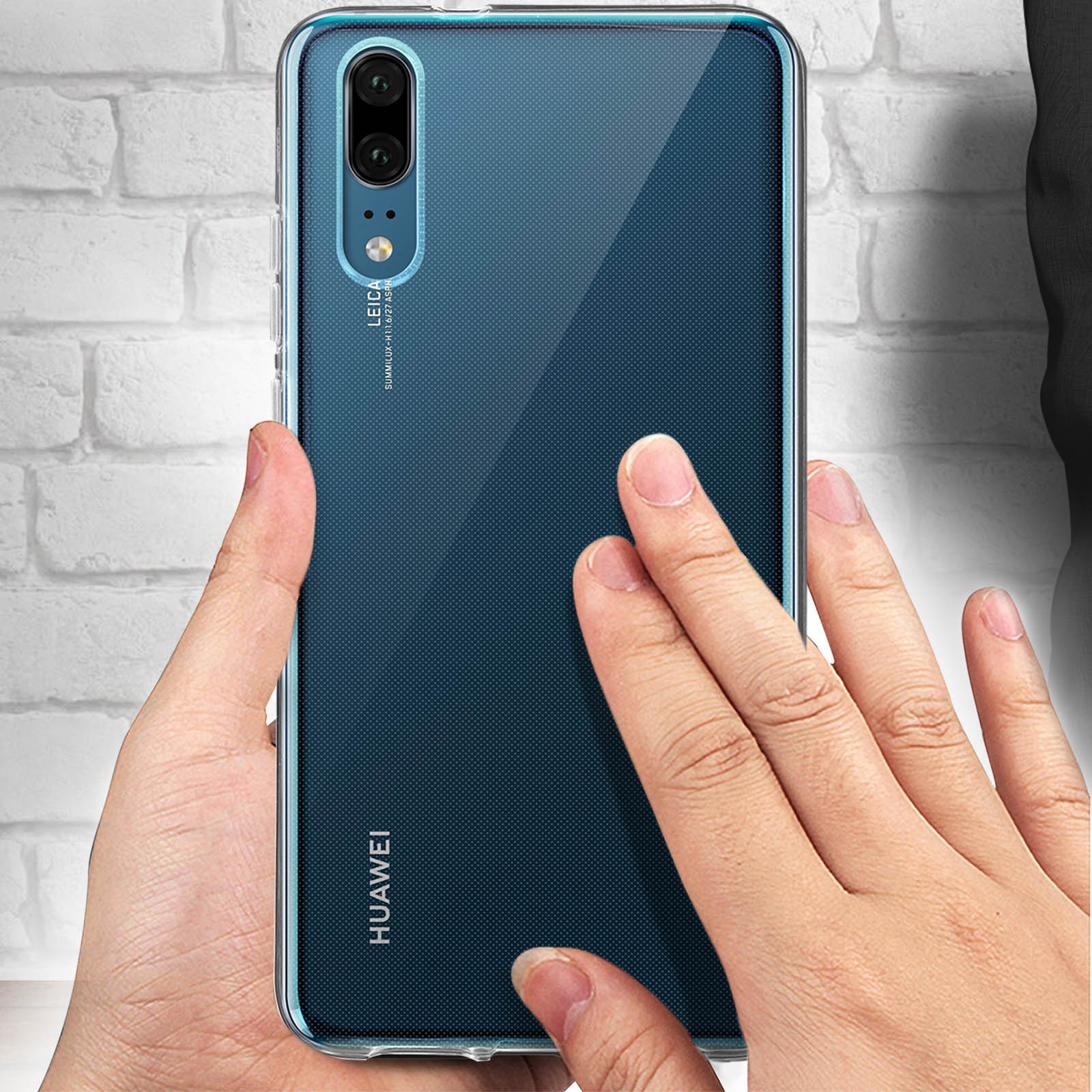 Mani che tengono un telefono con custodia trasparente. Il telefono ha più fotocamere. Sfondo: muro di mattoni.