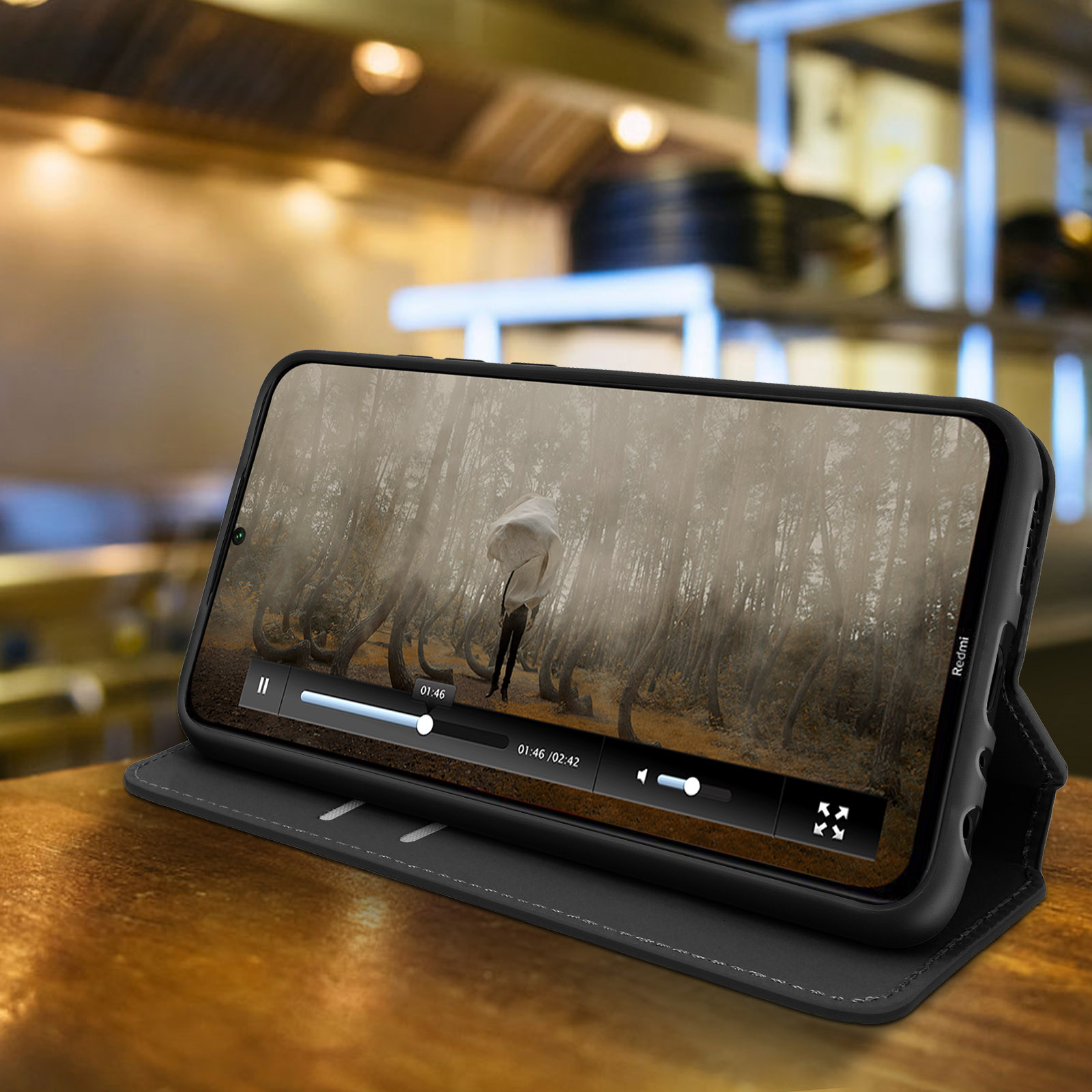 Téléphone dans un étui jouant une vidéo. Une personne avec un parapluie dans la forêt est à l'écran.