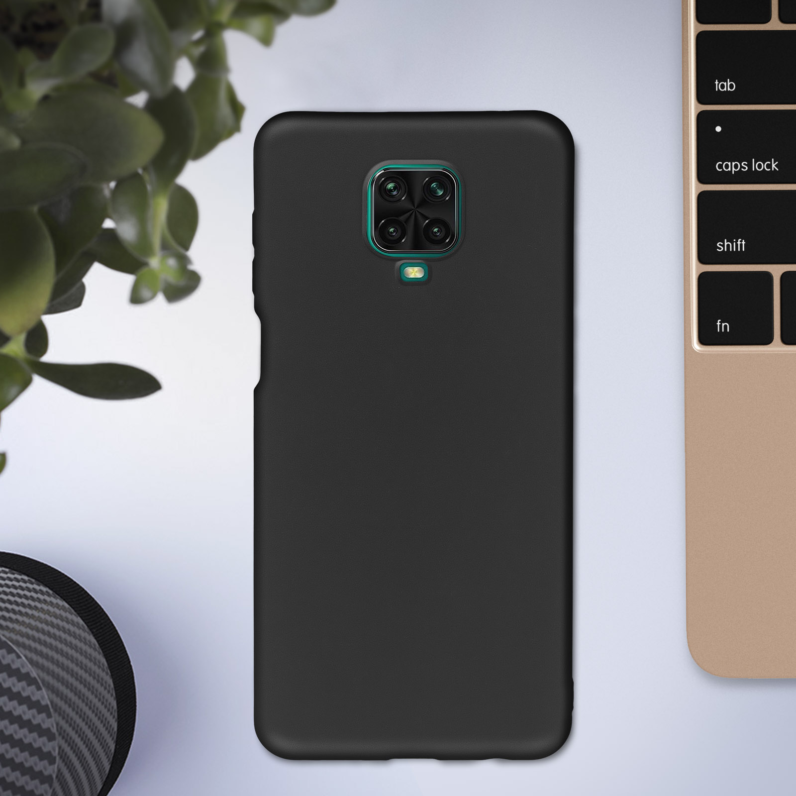 Zwarte telefoonhoes met cameramodule. Plant en laptop toetsenbord op de achtergrond.