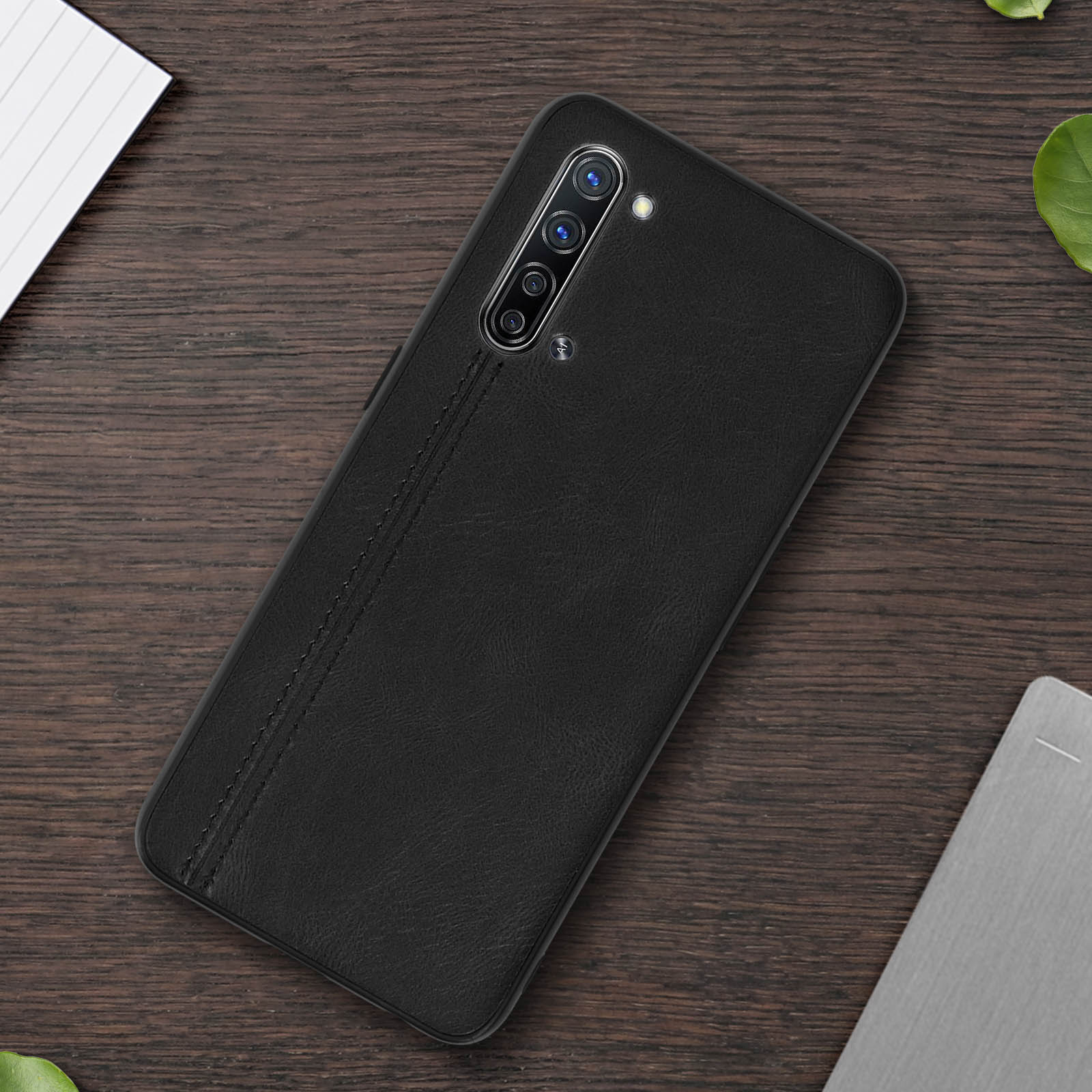 Custodia per telefono nera su superficie di legno. Ha una configurazione della fotocamera e una cucitura sul retro.