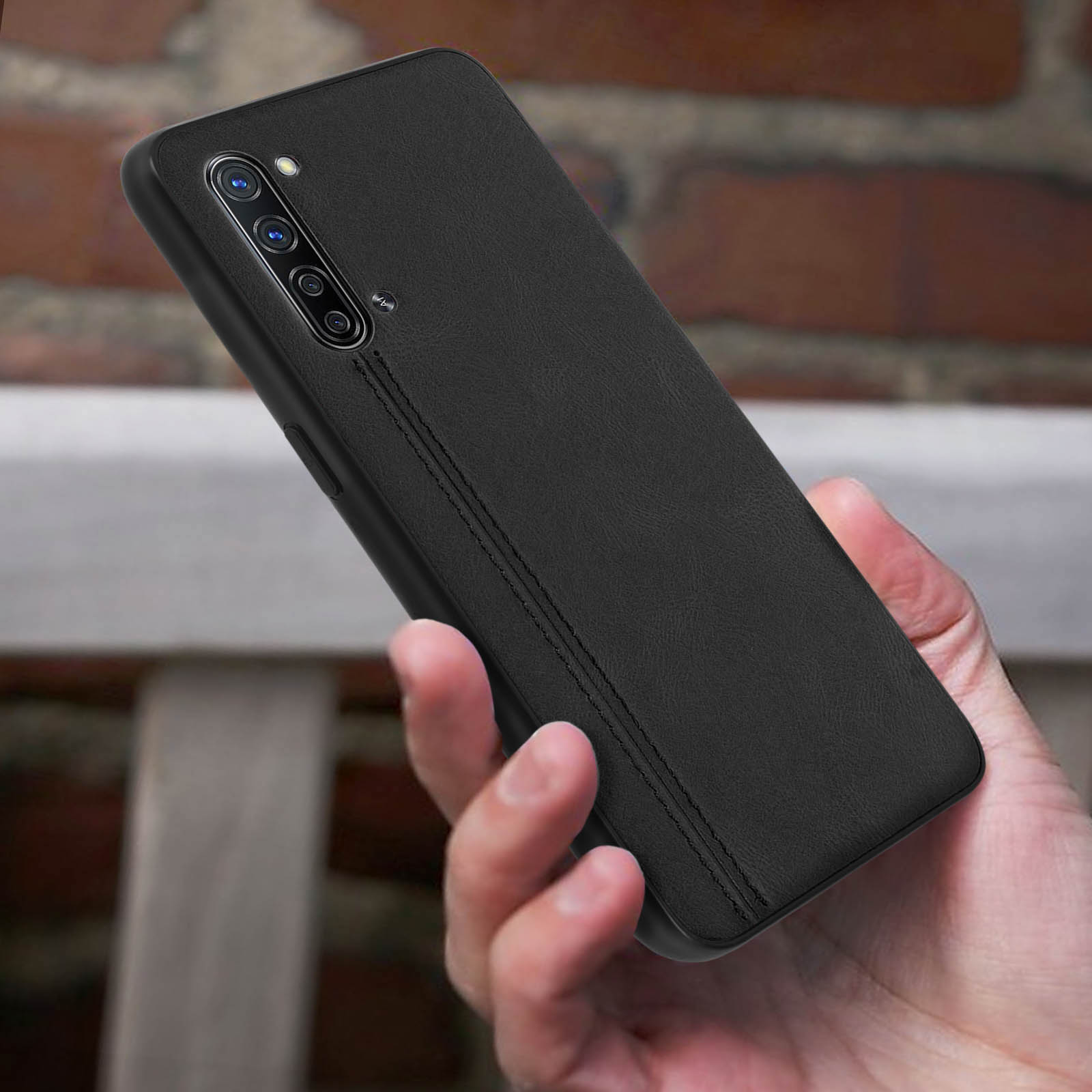 Una mano tiene una custodia nera per telefono con un design cucito. Lo sfondo è una mano.