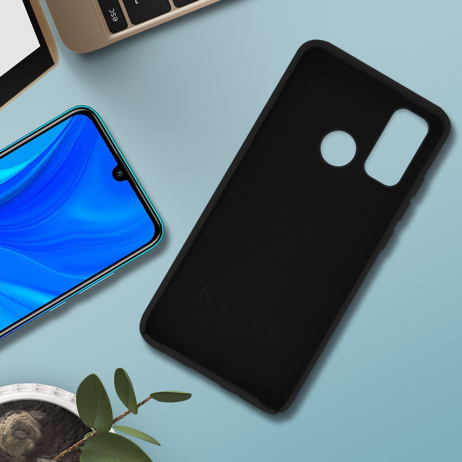 Custodia nera per telefono e telefono con icone di app, su superficie blu con foglia e tastiera.