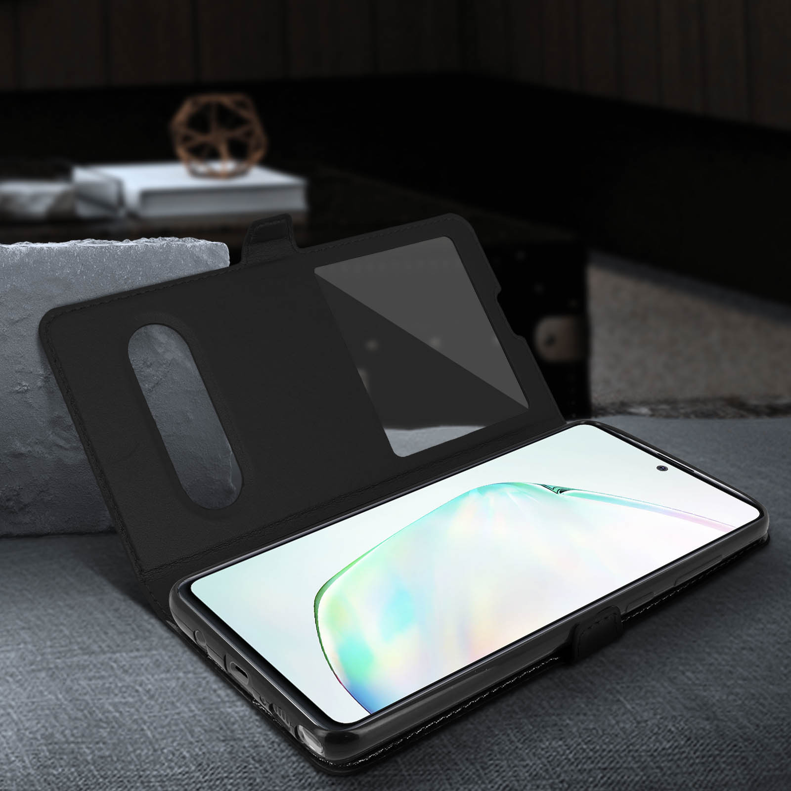 Un téléphone noir dans un étui en cuir, partiellement ouvert. L'écran affiche un motif flou et coloré.