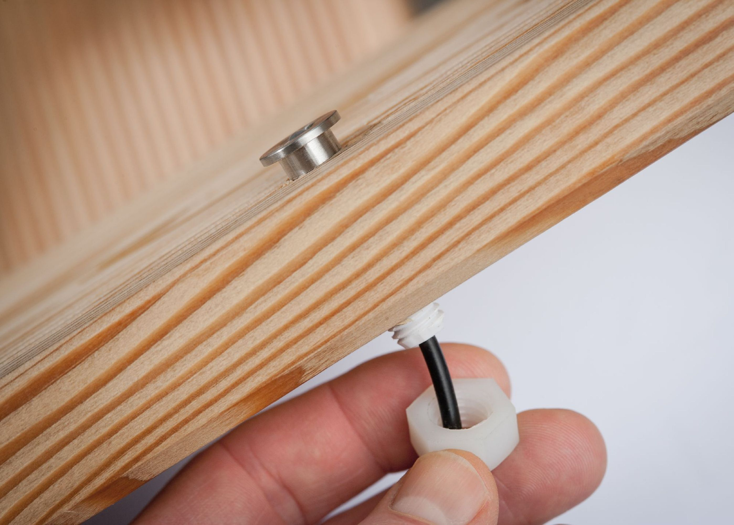 Primo piano di pezzi di legno con vite metallica e filo nero. Sfondo bianco, dettaglio.