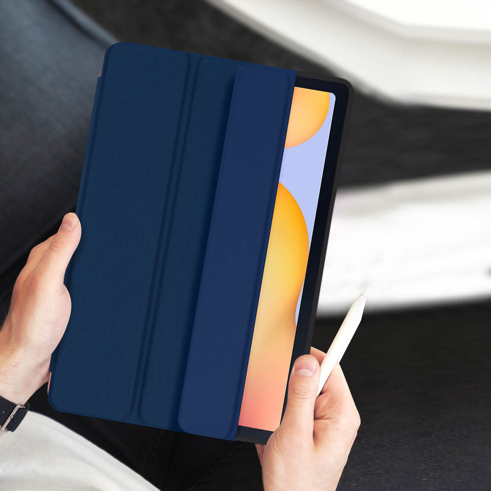 Tablet in einer blauen Hülle, gehalten von Händen. Die Hülle ist offen, der Bildschirm sichtbar.