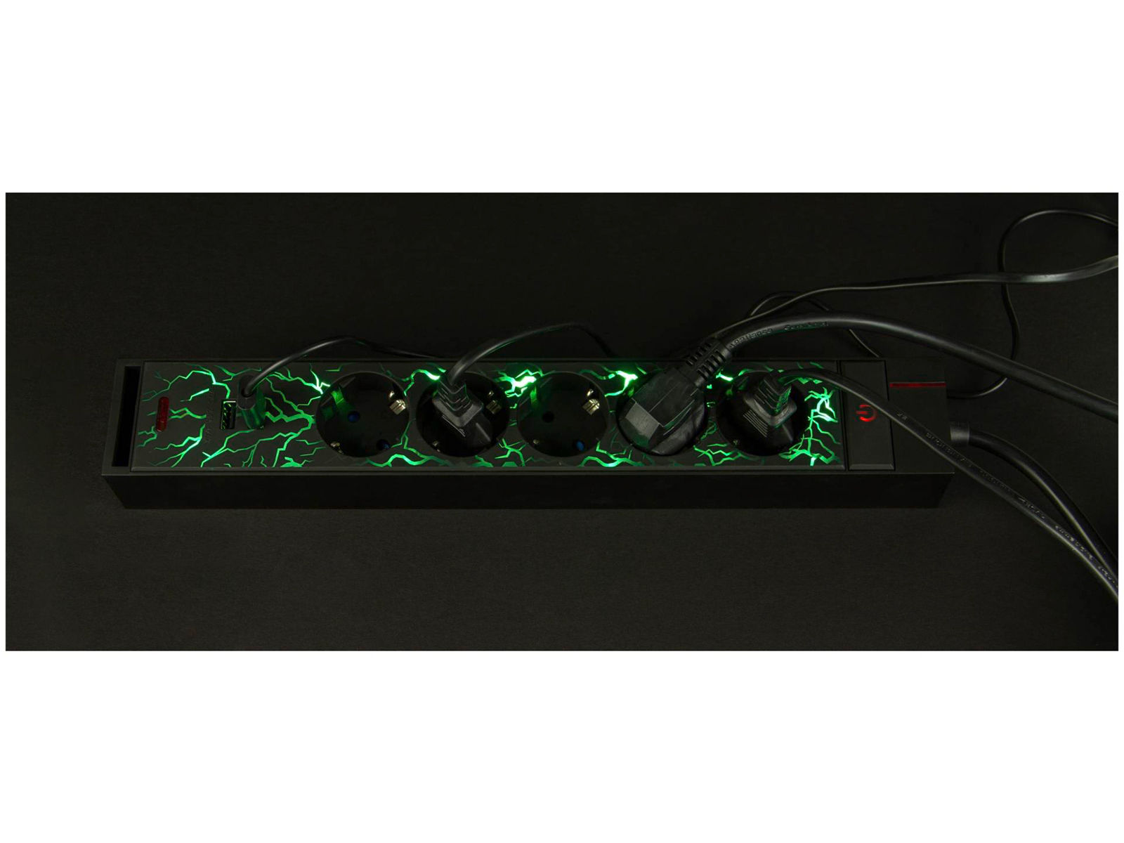Eine schwarze Steckdosenleiste mit mehreren Steckdosen, beleuchtet von grünen Lichtern. Kabel sind eingesteckt.