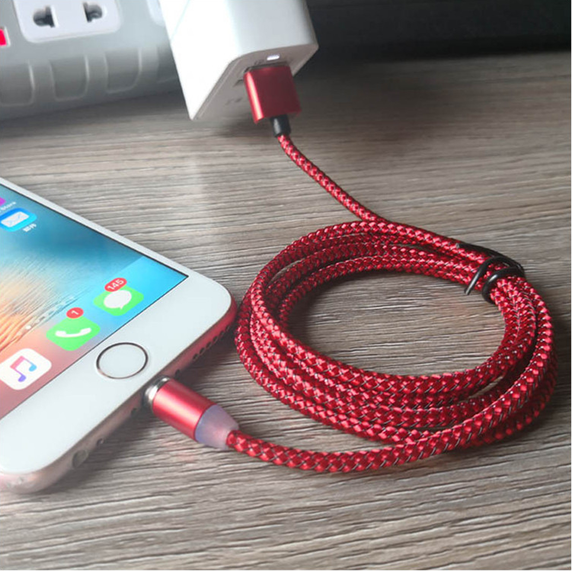 Ein rotes Kabel lädt ein Telefon mit roter Spitze und weißem Ladegerät auf.