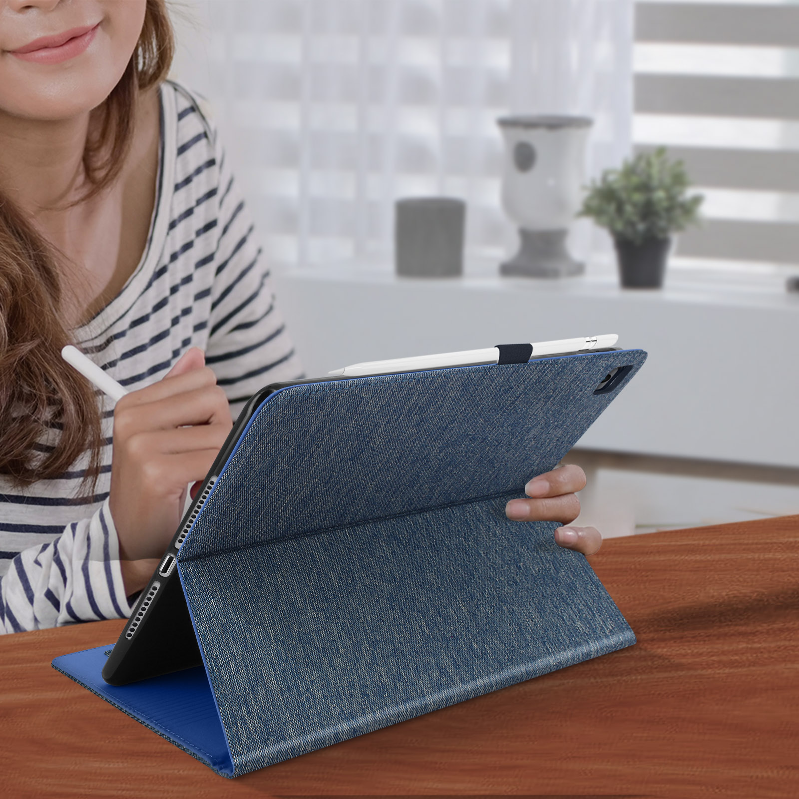 Donna che usa un tablet con una custodia in stile denim, che tiene uno stilo.