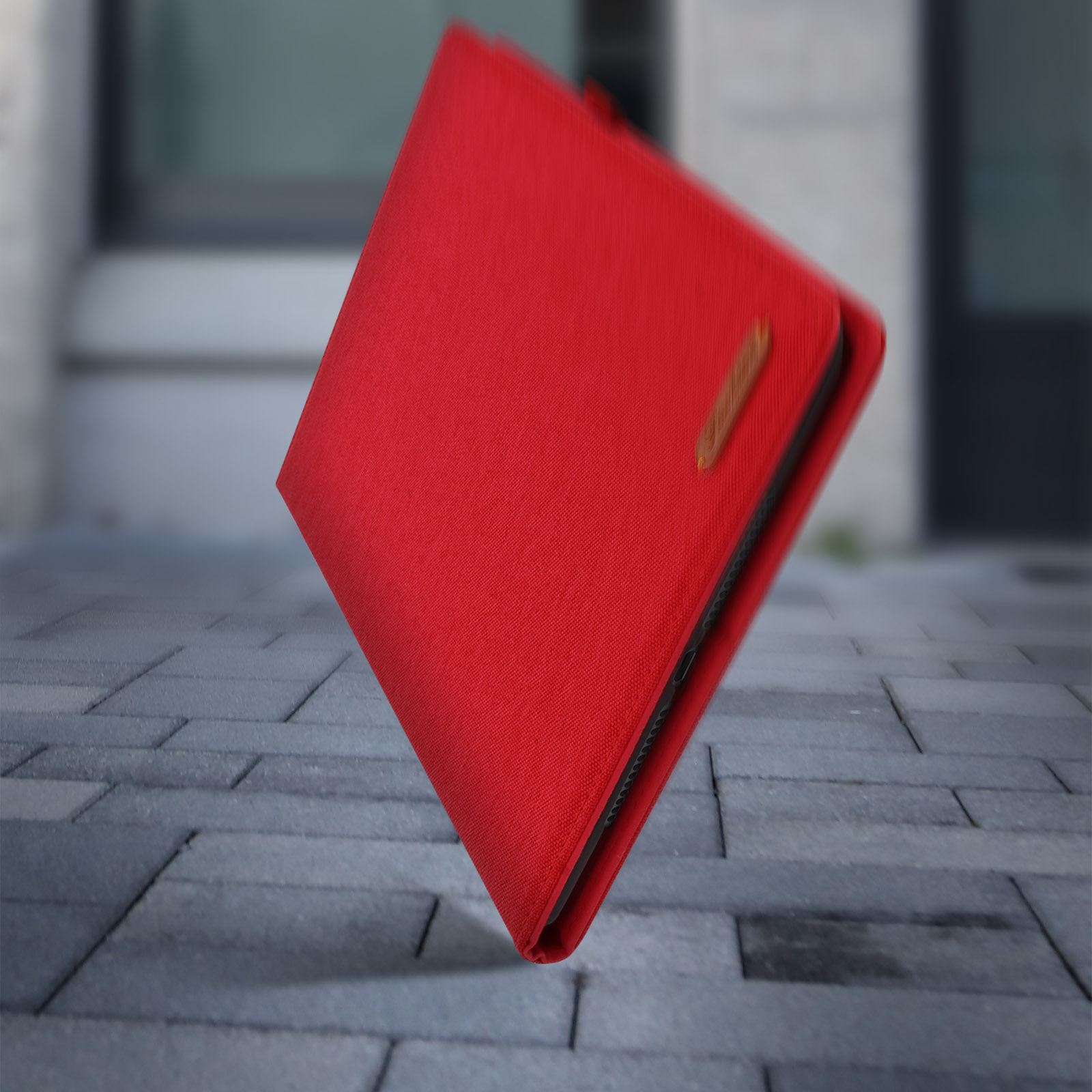 Una custodia per telefono rossa cade su una superficie pavimentata.