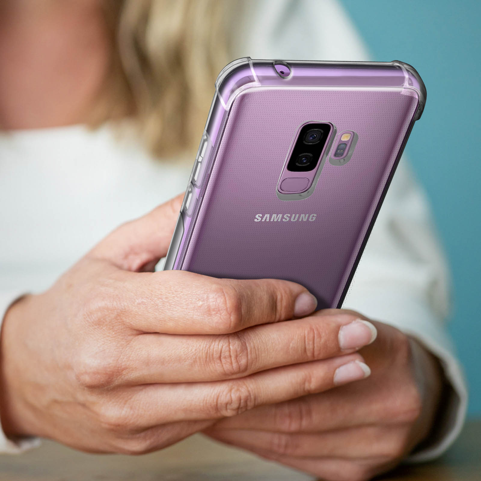 Una persona tiene in mano un telefono viola in una custodia trasparente. Il telefono è un Samsung.