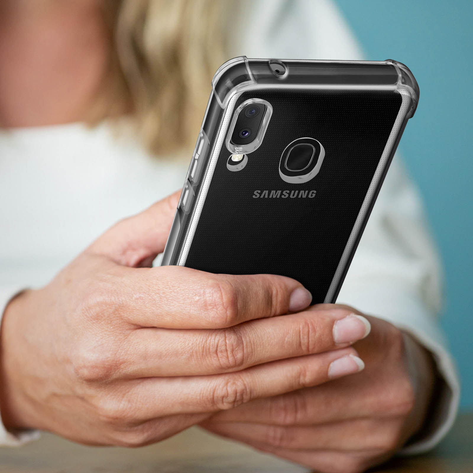 Un telefono con una custodia trasparente, tenuto in mano. Il telefono ha una fotocamera e un logo Samsung.
