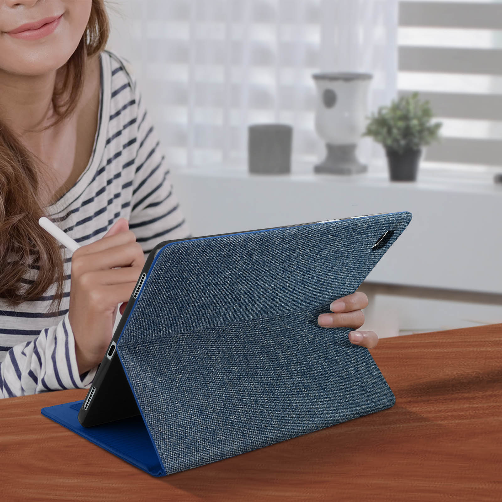 Donna con tablet in una custodia blu. Una penna bianca in mano.