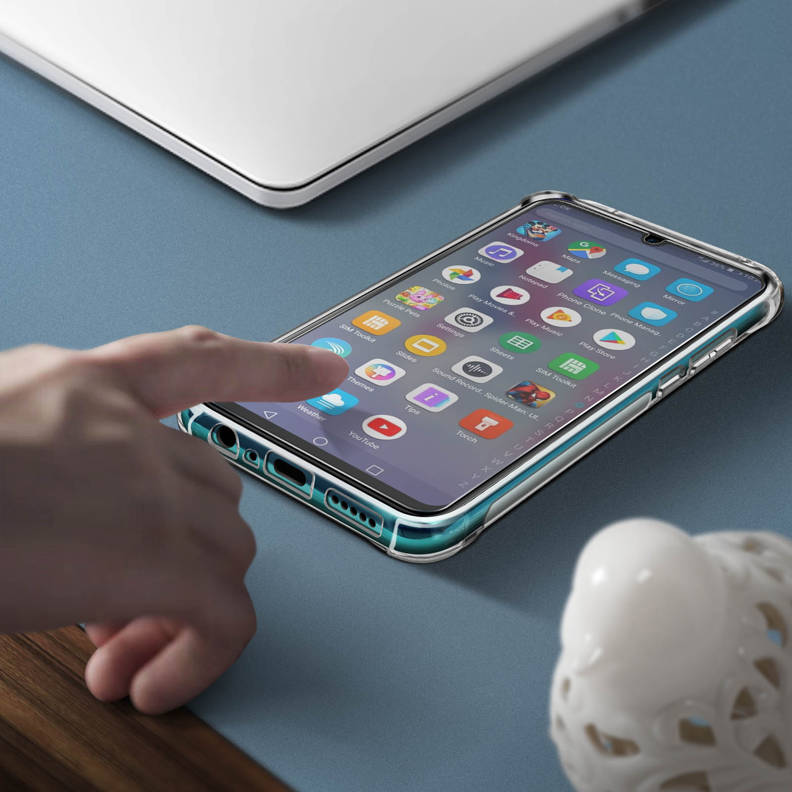 Un telefono con icone visualizzate è su una scrivania. Una mano tocca lo schermo. Un laptop è anche sulla scrivania.