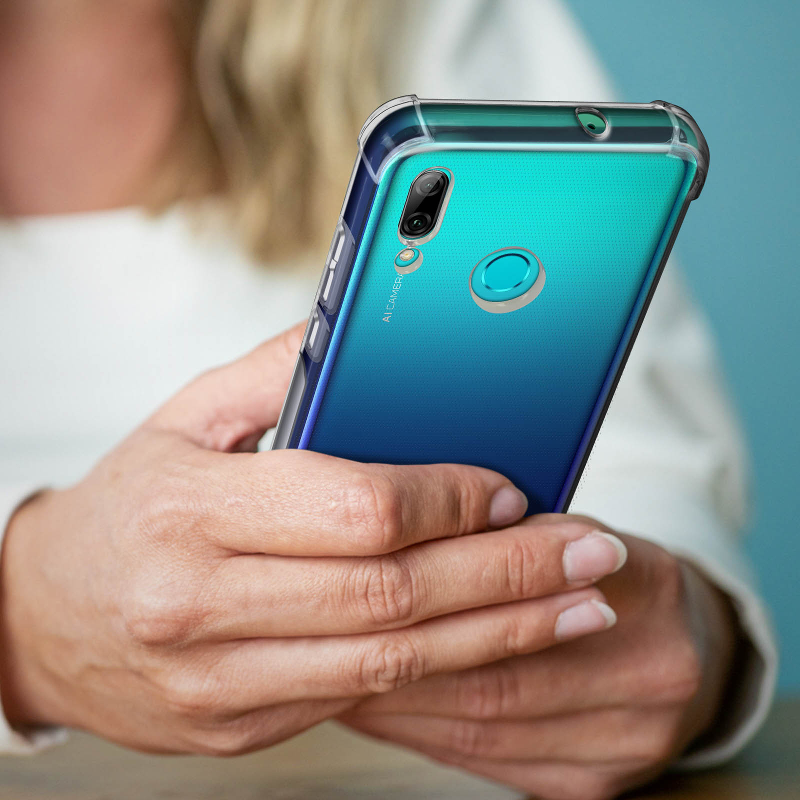 Una persona tiene in mano un telefono con una custodia trasparente. Il telefono ha un retro sfumato e una fotocamera.