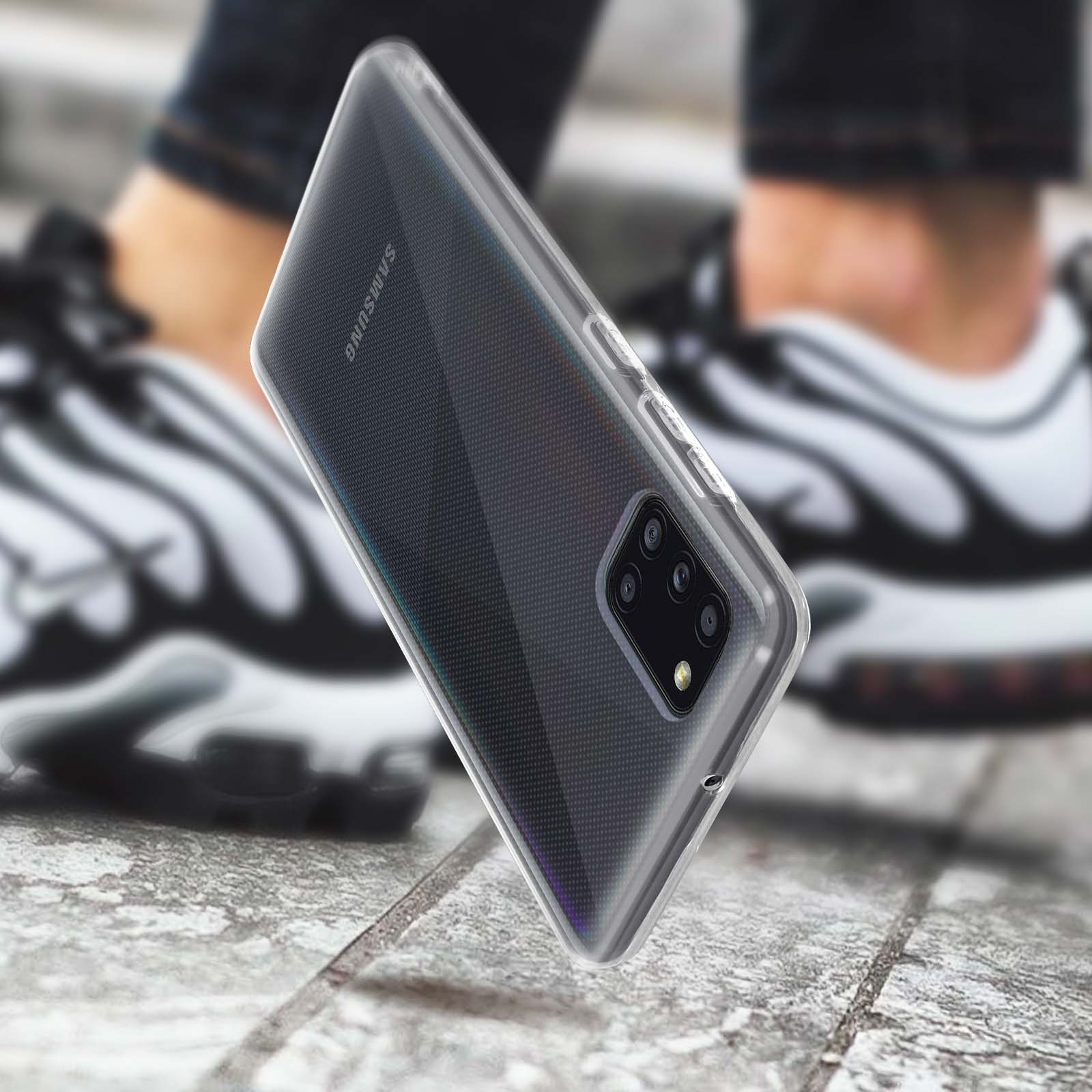Une coque de téléphone avec un dos transparent est mise au point, sur un arrière-plan flou. Une personne est en arrière-plan.