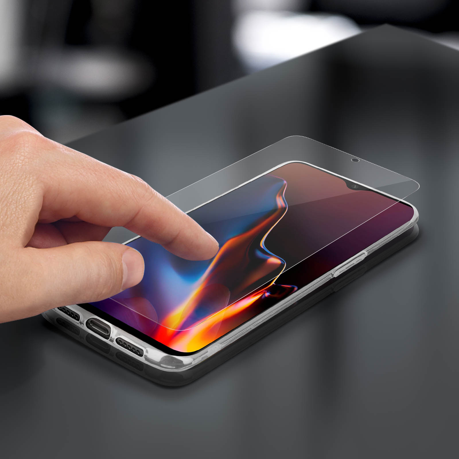 Mano tocca schermo del telefono con protezione. Sfondo tavolo nero.
