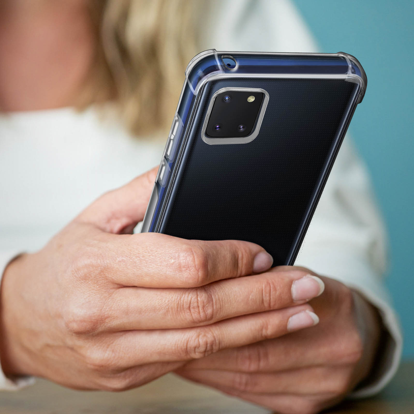 Una mano che tiene una custodia blu per telefono con un telefono nero all'interno. La custodia ha una cornice blu scuro.