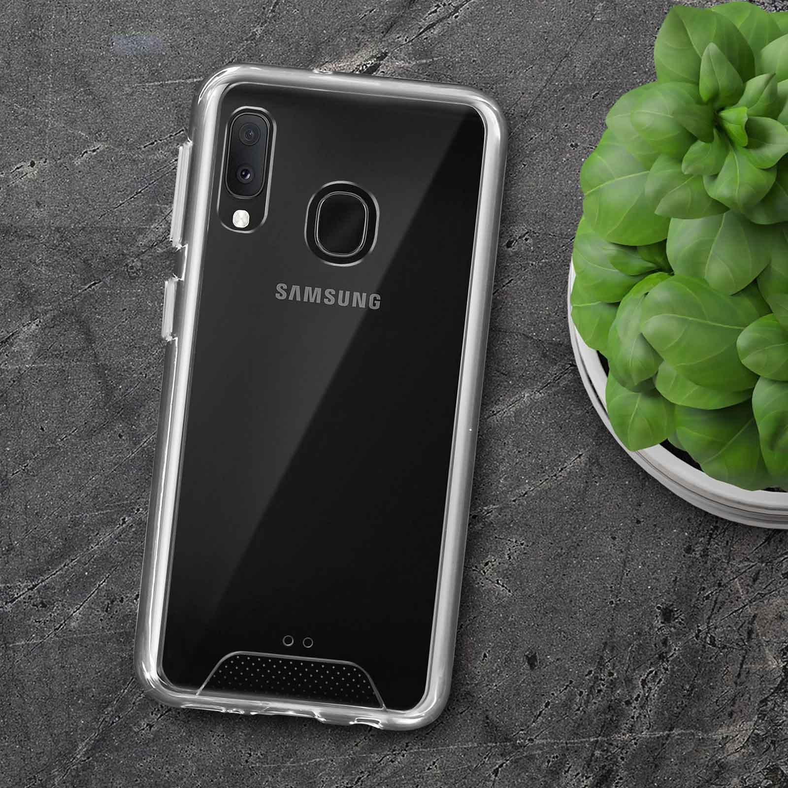 Custodia trasparente per telefono su un telefono nero. Pianta sullo sfondo. Il telefono è appoggiato su una superficie grigio scuro.