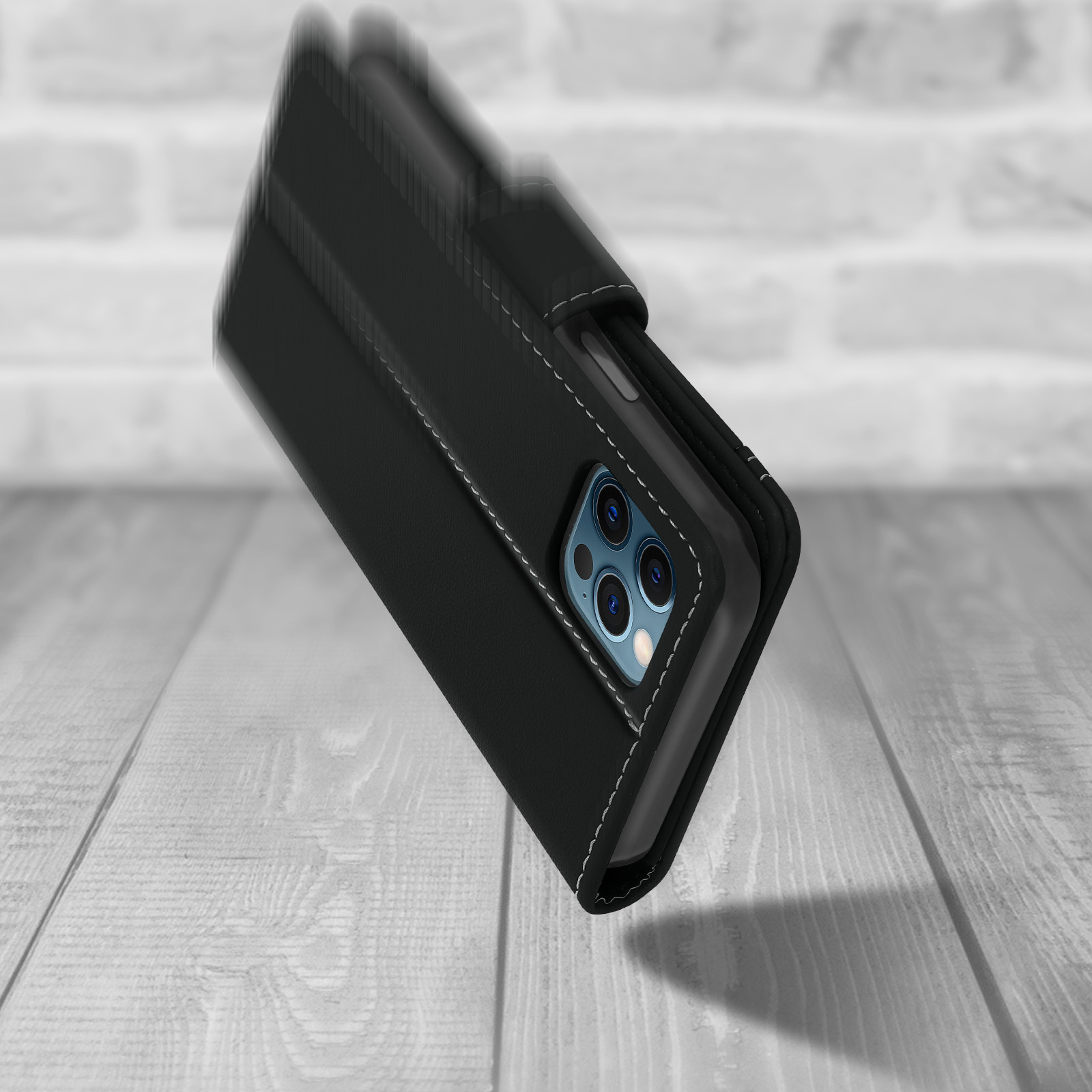 Zwarte telefoonhoes met witte stiksels. Telefoon staat schuin op een houten oppervlak.