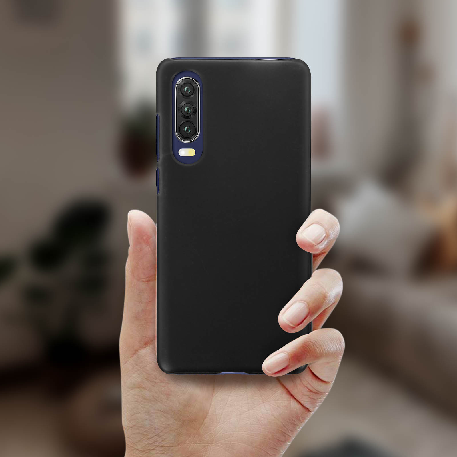 Una mano che tiene una custodia nera per telefono. Il telefono ha tre fotocamere. Sfondo sfocato.