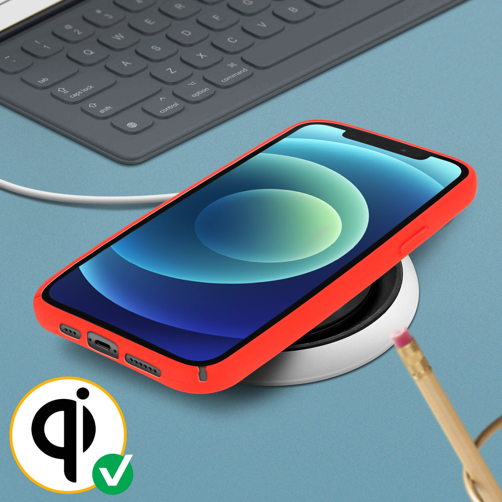 Telefoon op draadloze oplader, met potlood en toetsenbord. Achtergrond: blauw oppervlak.